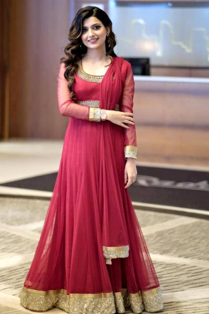 身穿紅金傳統印度服飾的女性在室內擺姿勢。