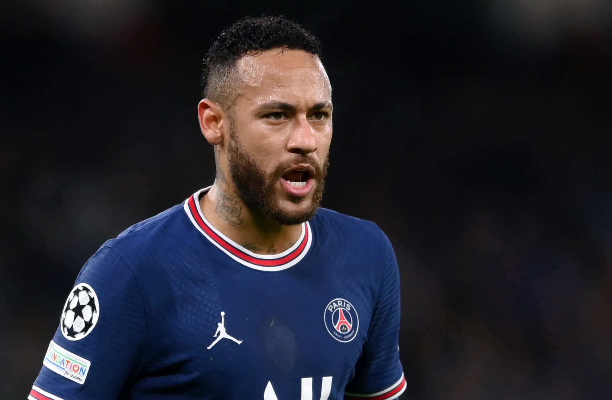 Neymar 桌布 壁紙 — 尼馬身穿巴黎聖日耳曼球衣在夜間足球比賽中的特寫，球場燈光映照出他專注的表情。