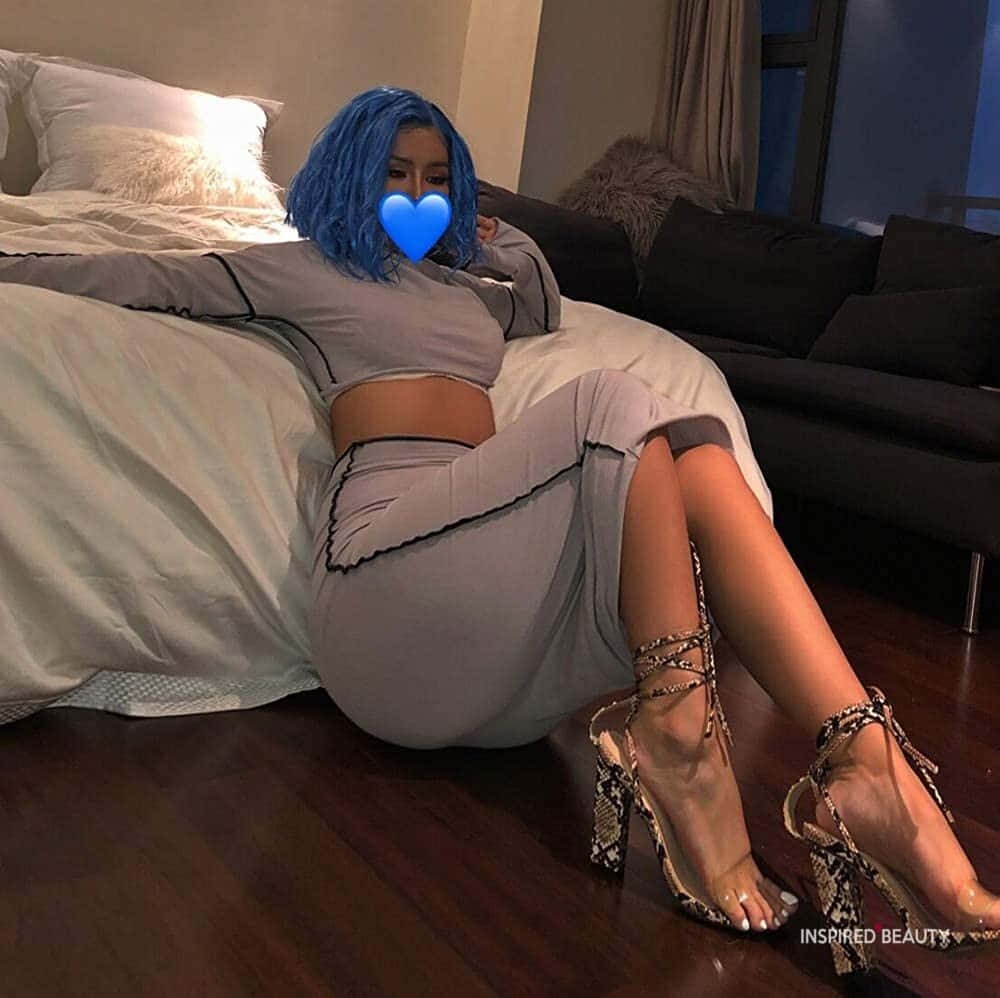 藍色頭髮嘅人着住灰色衫同蛇皮高踭鞋喺床上攤唞。 — Baddie 美學 壁紙