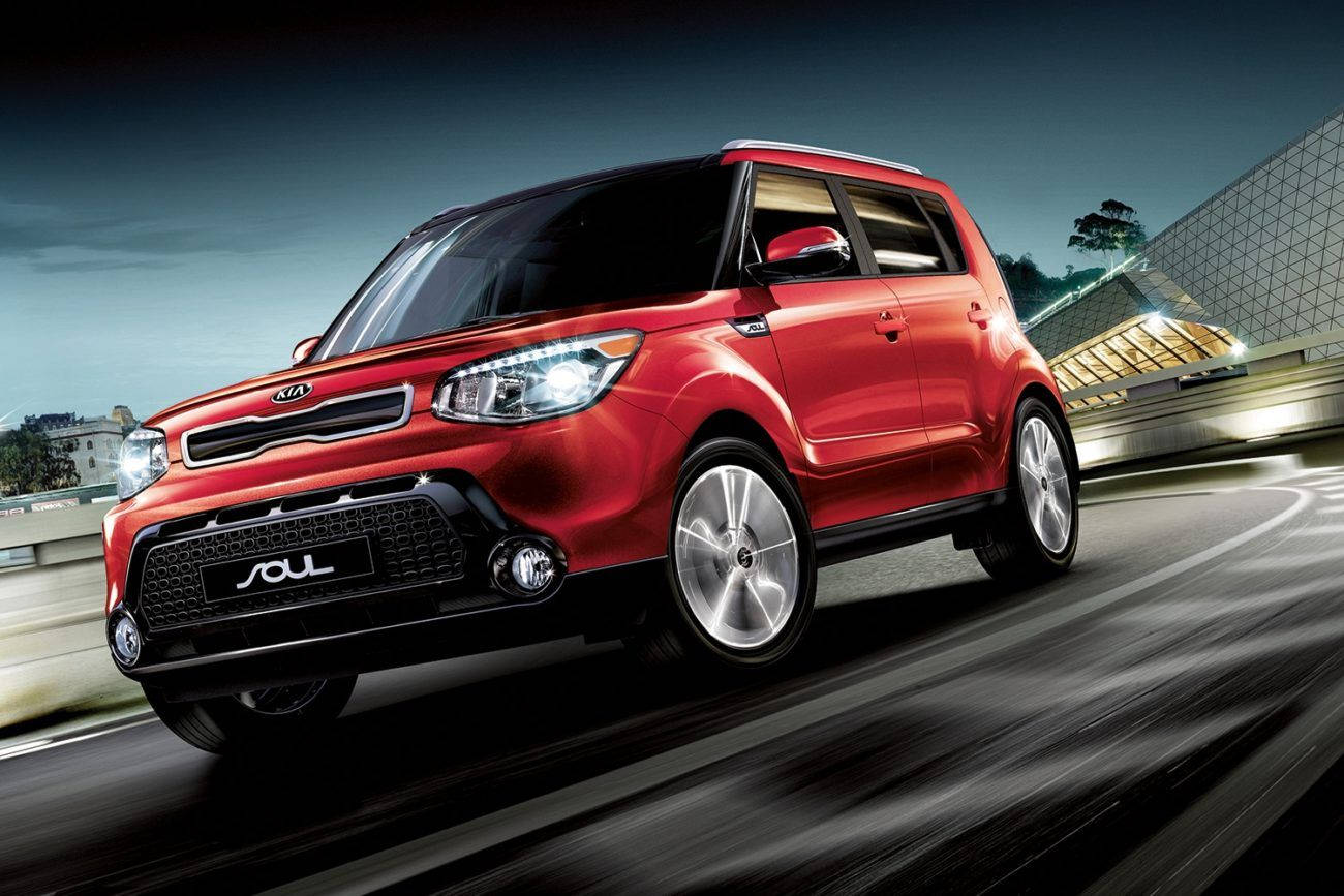 紅色Kia Soul汽車在夜間的城市高速公路上飛馳。
