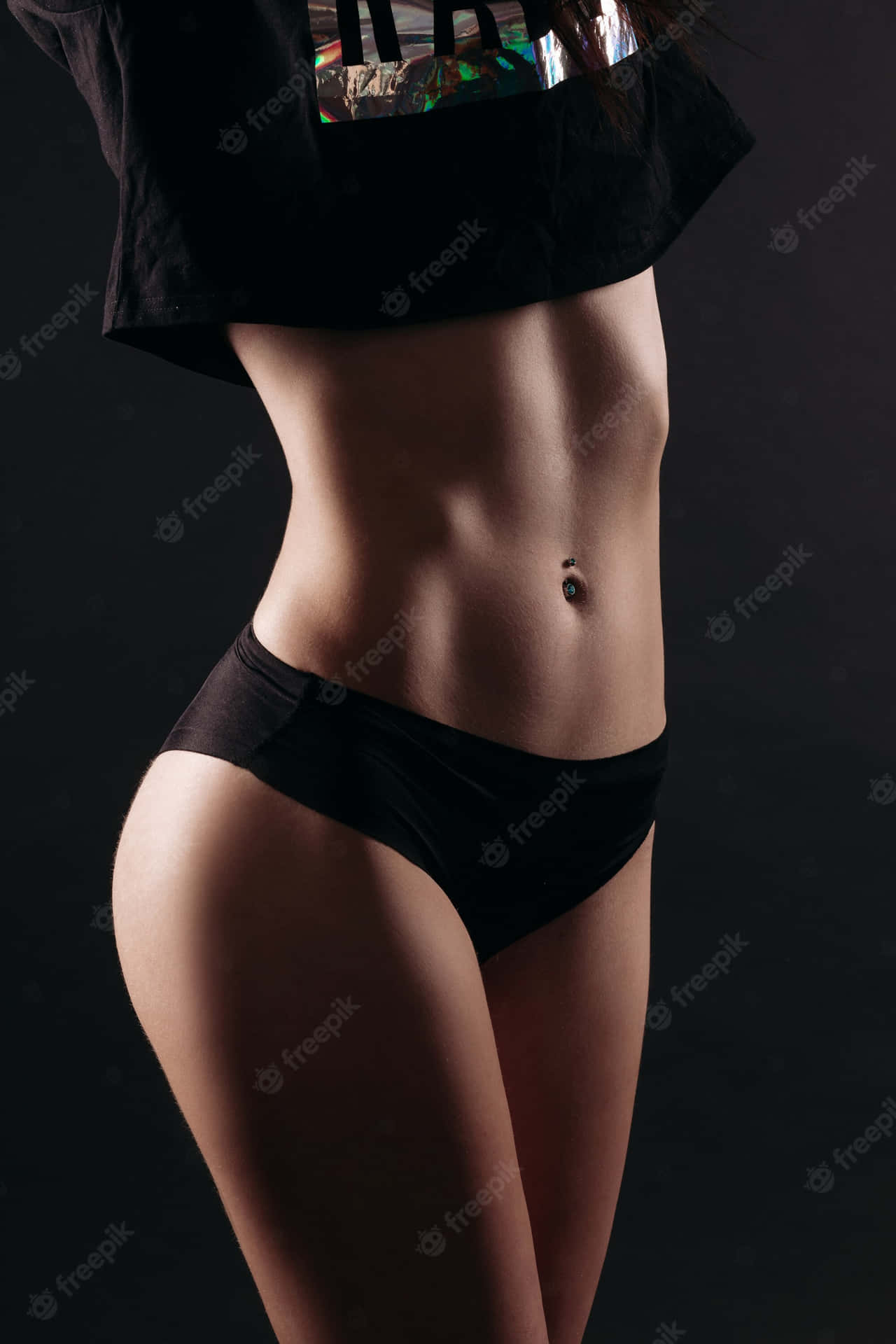 特寫一位穿著黑色內衣的女性，在深色背景下展現其結實的軀幹和臀部。