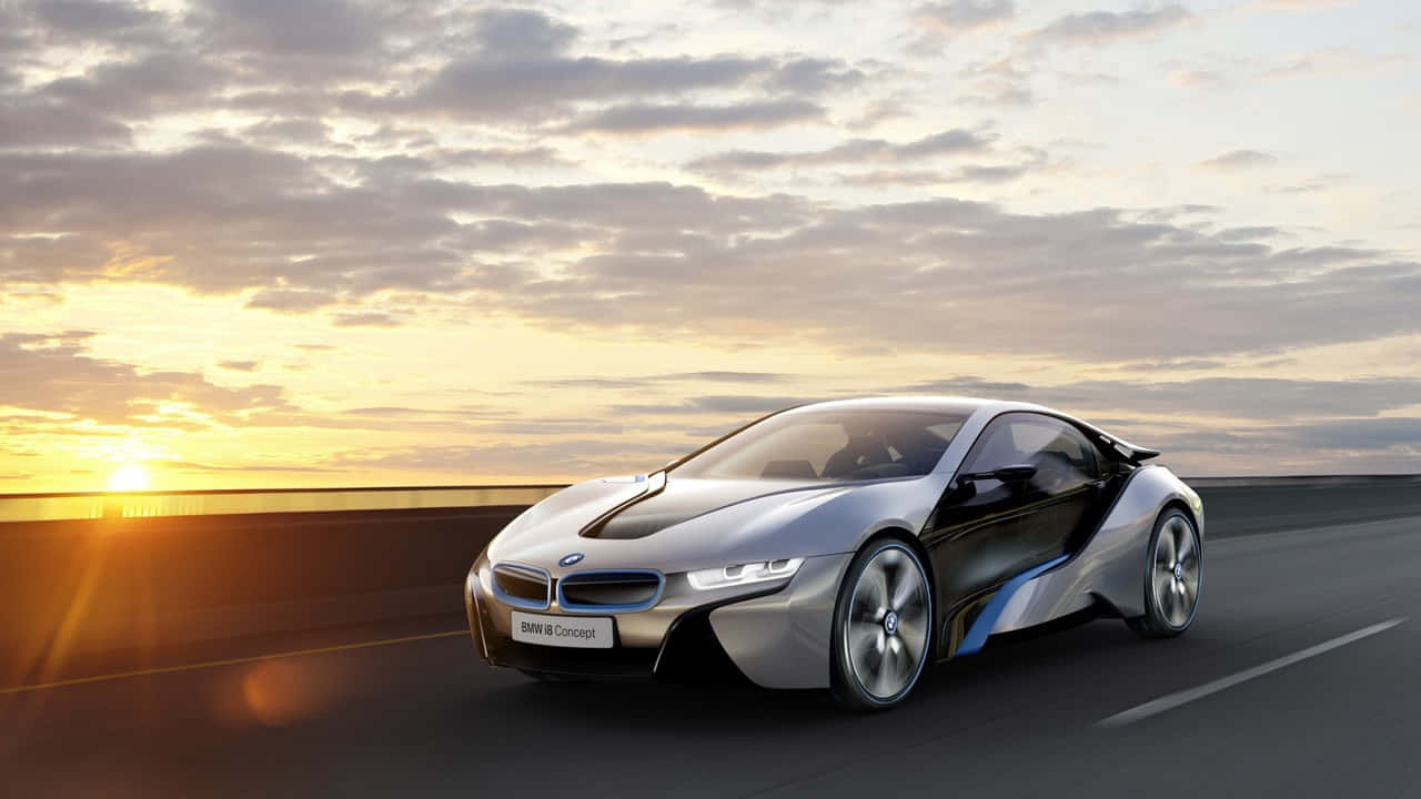 展現您的流線型寶馬 壁紙 — 一輛時尚的銀色BMW i8 Concept跑車在日落時分沿著高速公路行駛，伴隨著金色的雲彩和發光的地平線。