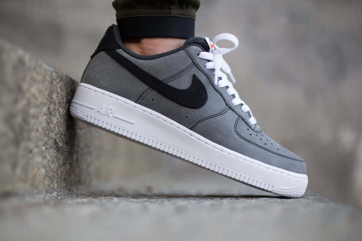 灰色Nike Air Force 1運動鞋配白色鞋帶在石階上。