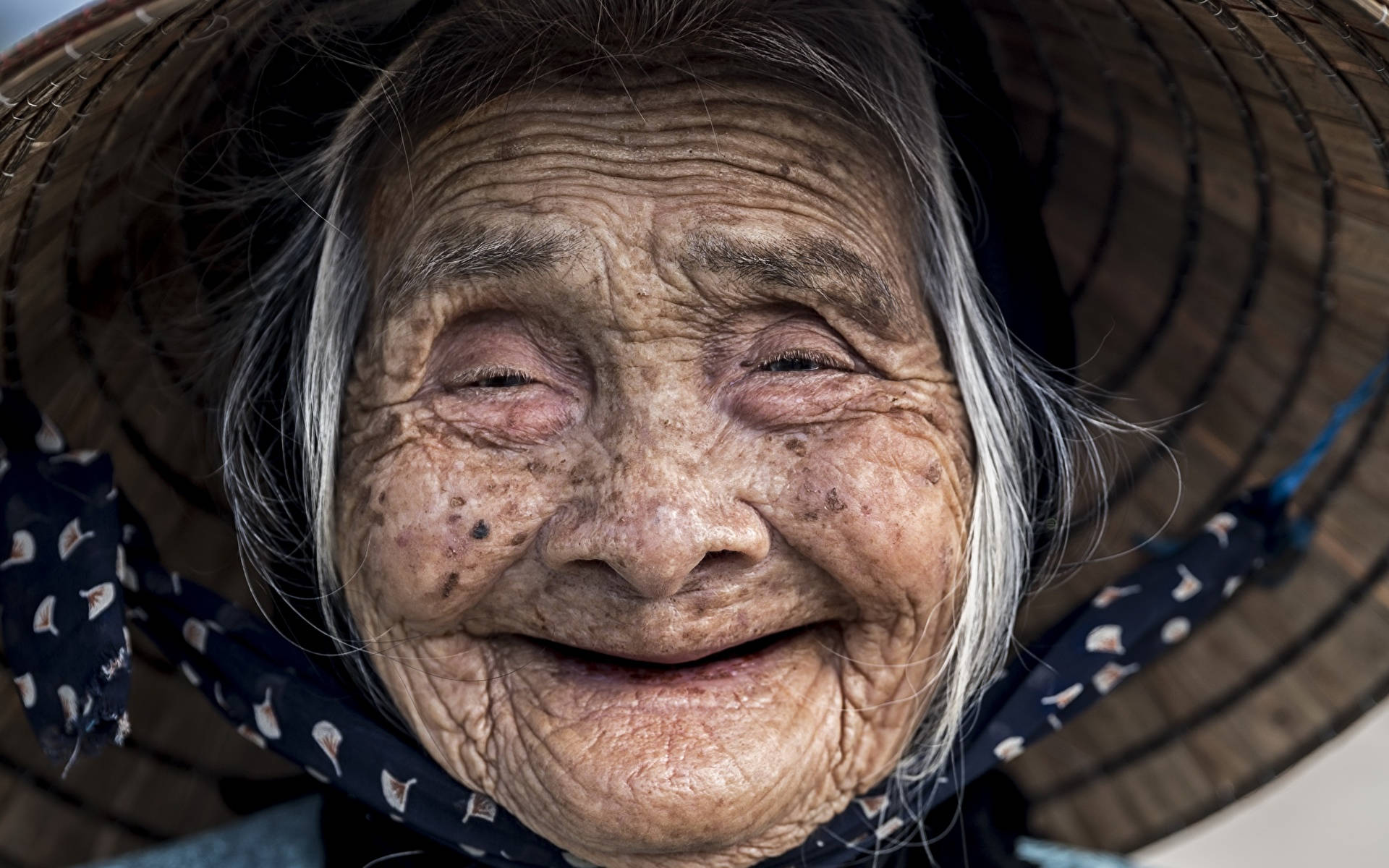 一位笑容燦爛的老年婦女戴著編織草帽。