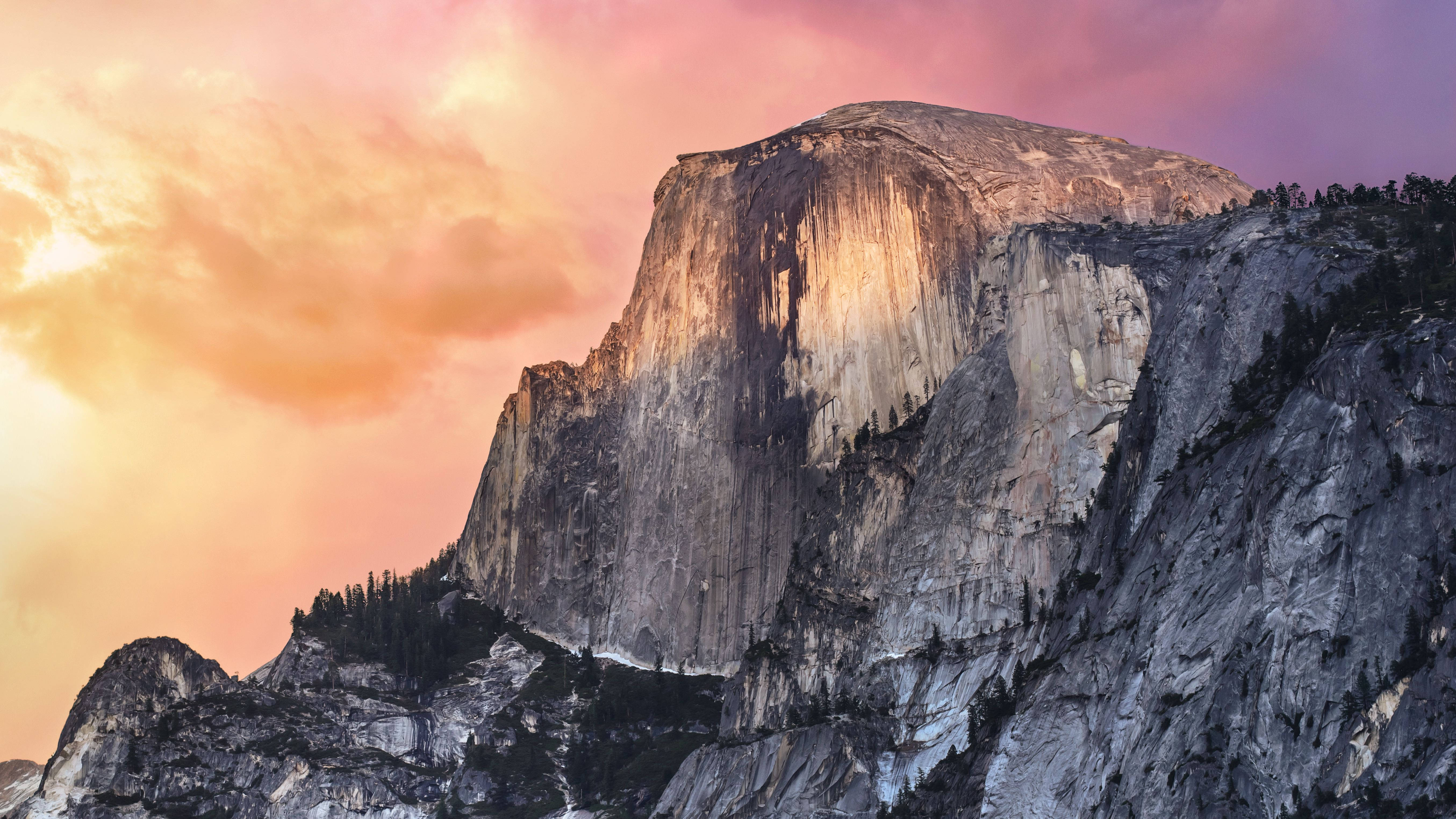 山崖 MacBook Pro 4K 壁紙 — 半圓頂山沐浴在金色夕陽的光芒中，映襯著充滿活力的粉紅色和橙色天空。