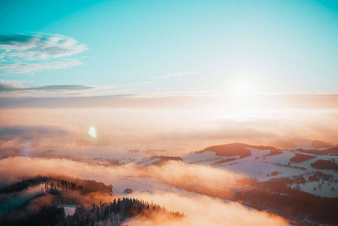 雪山和森林沐浴在日出光芒中，薄霧在山谷間翻滾。