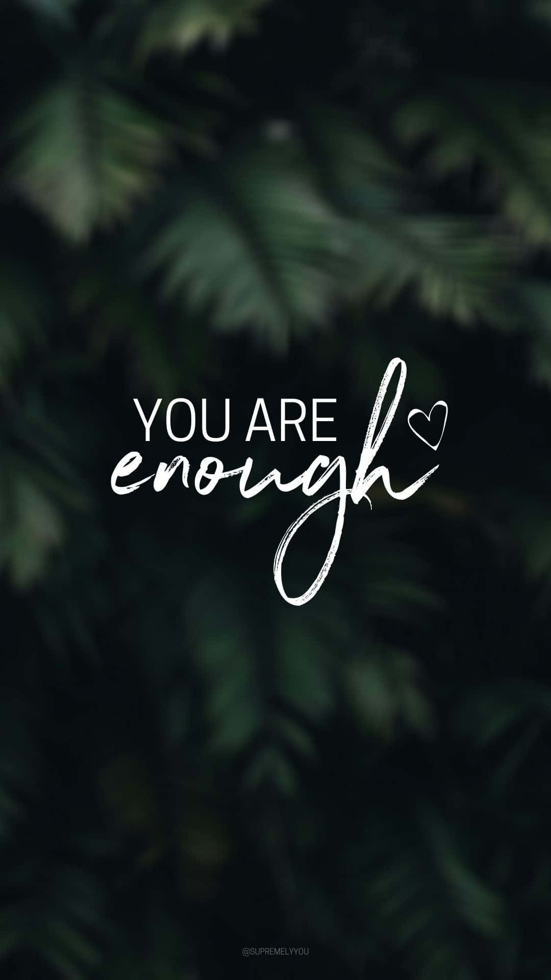在深綠色樹葉上以白色字體書寫的勵志名言 you are enough。