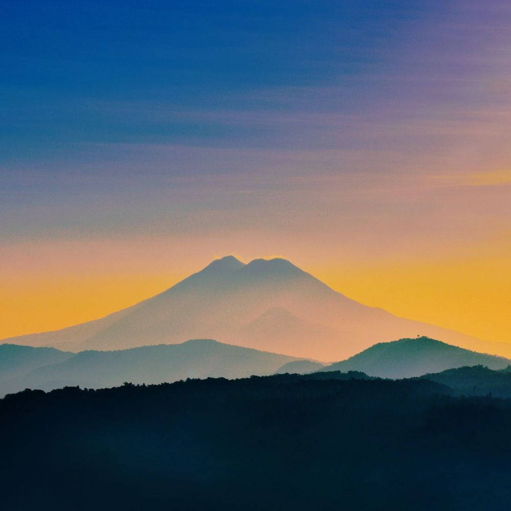 黎明時分，藍紫色和橙色漸變天空下的山脈輪廓。