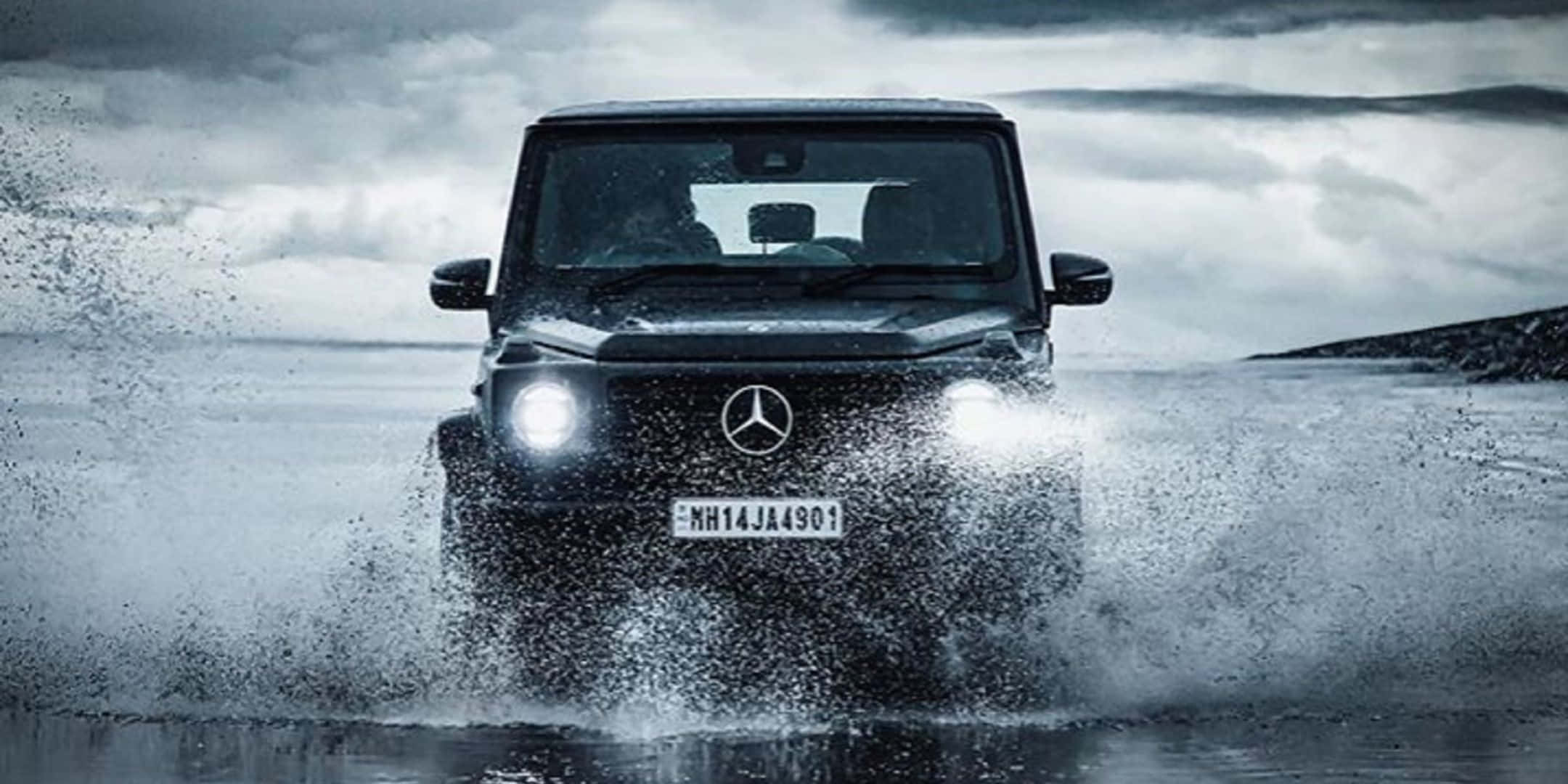 黑色 Mercedes G-Wagen 在暴風雲下車頭燈亮著行駛於深水中。