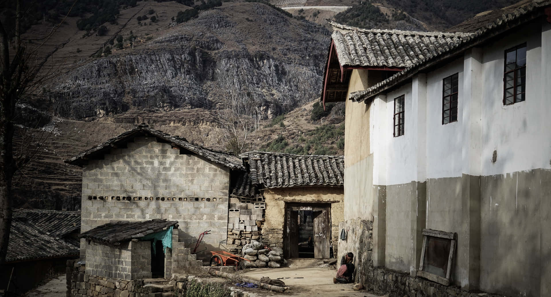 一個安靜的山村，有石屋和一個人坐在門口附近。