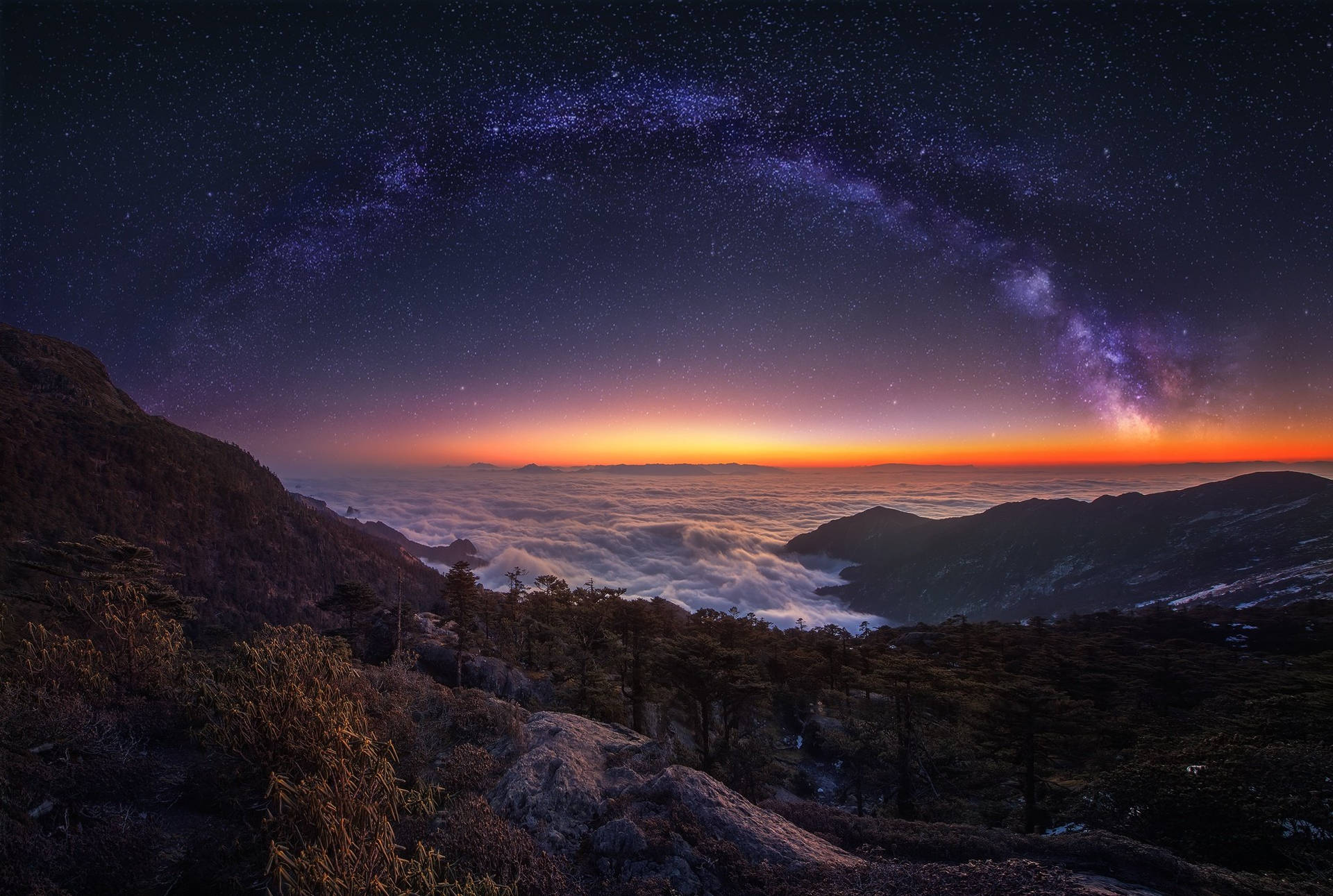 山峰在星空下升起於雲海之上，伴隨著銀河