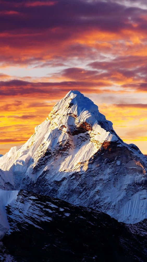 白雪覆蓋的山峰沐浴在金色夕陽光中，上方有彩色雲朵。
