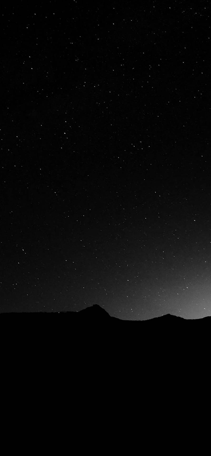 在帶有漸變地平線的星空夜空下的黑暗山脈。
