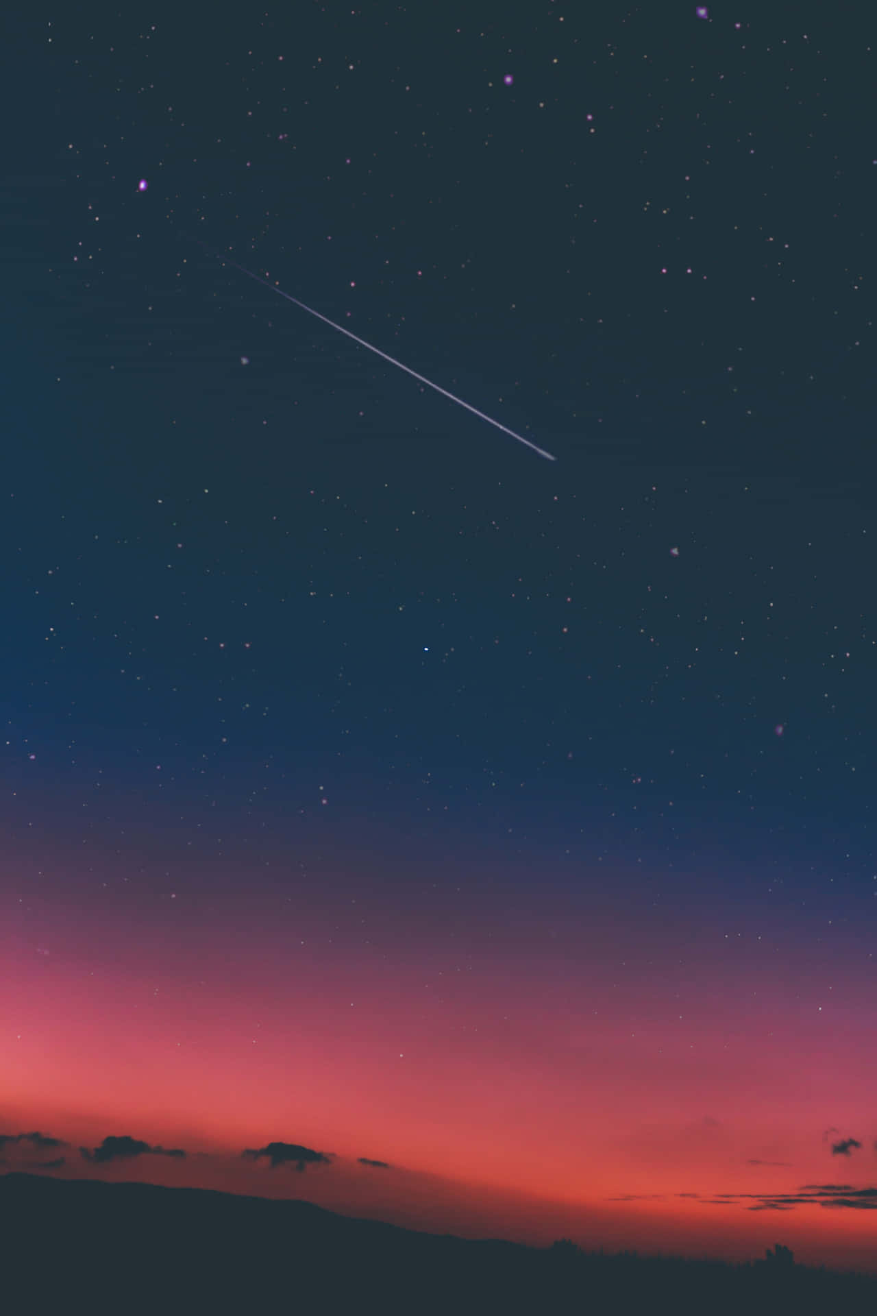一顆流星在剪影山丘上方的星空暮色天空中劃過。