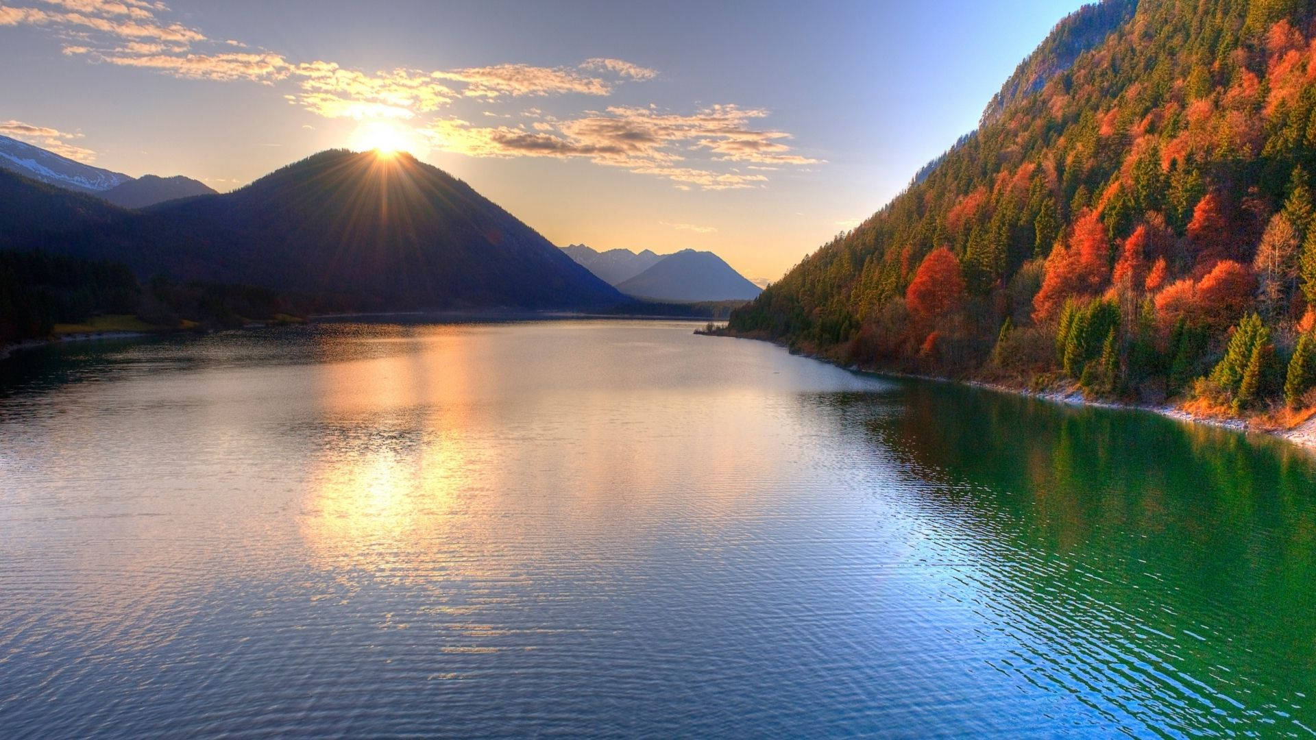 日落湖景，背景有秋樹和山脈