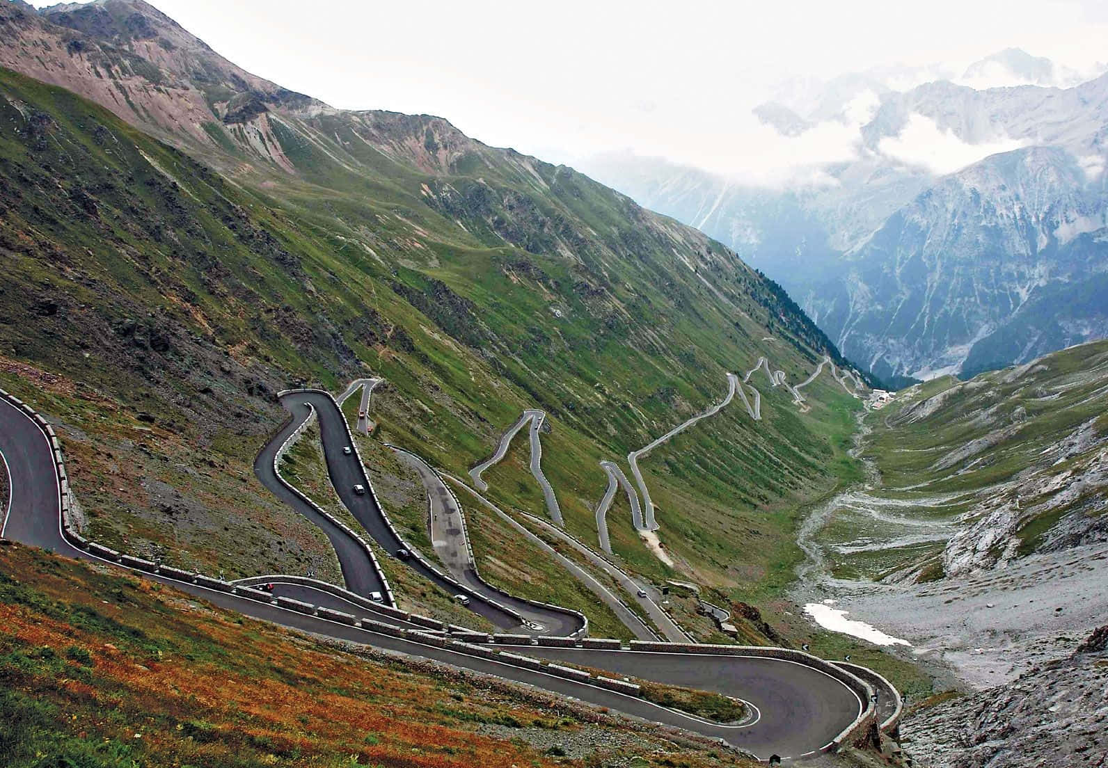 蜿蜒的山路，汽車在綠色和岩石地形上爬升。