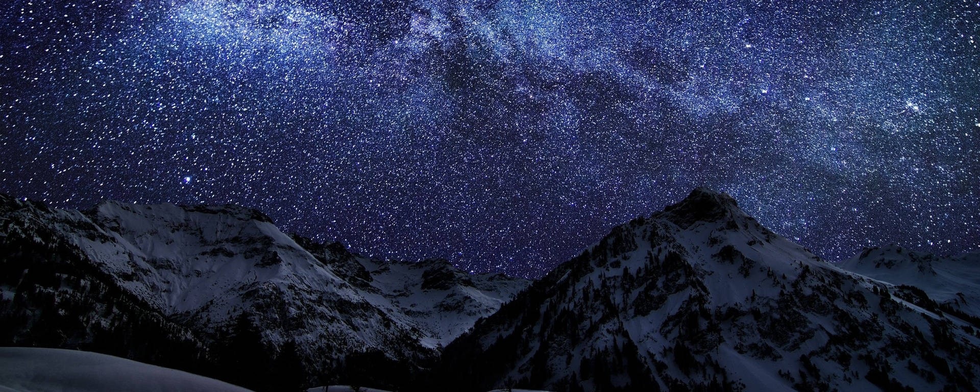 白雪覆蓋的山脈在明亮的星空下，銀河清晰可見。