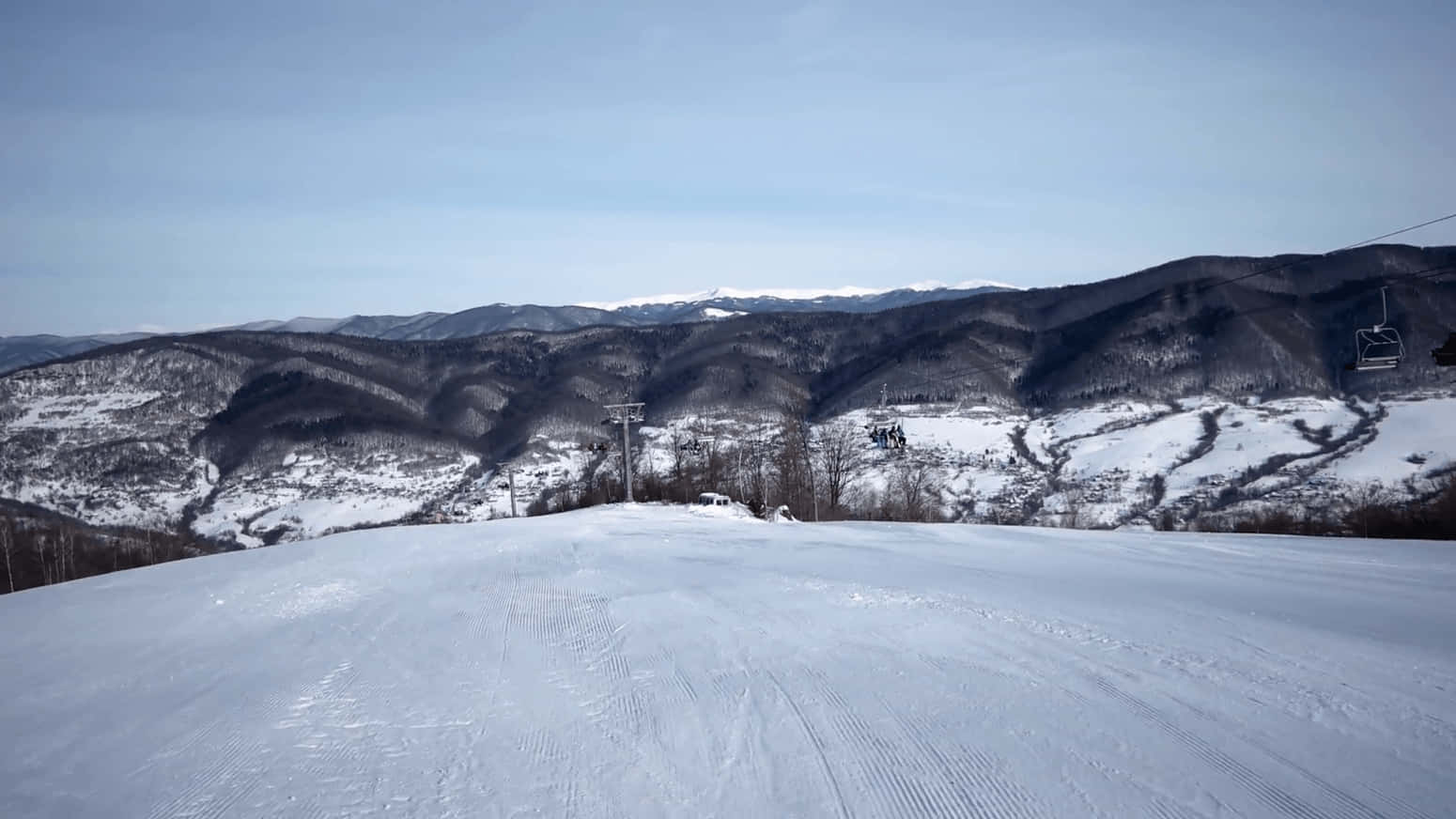 冬季的雪地滑雪道，設有纜車和森林覆蓋的山脈。