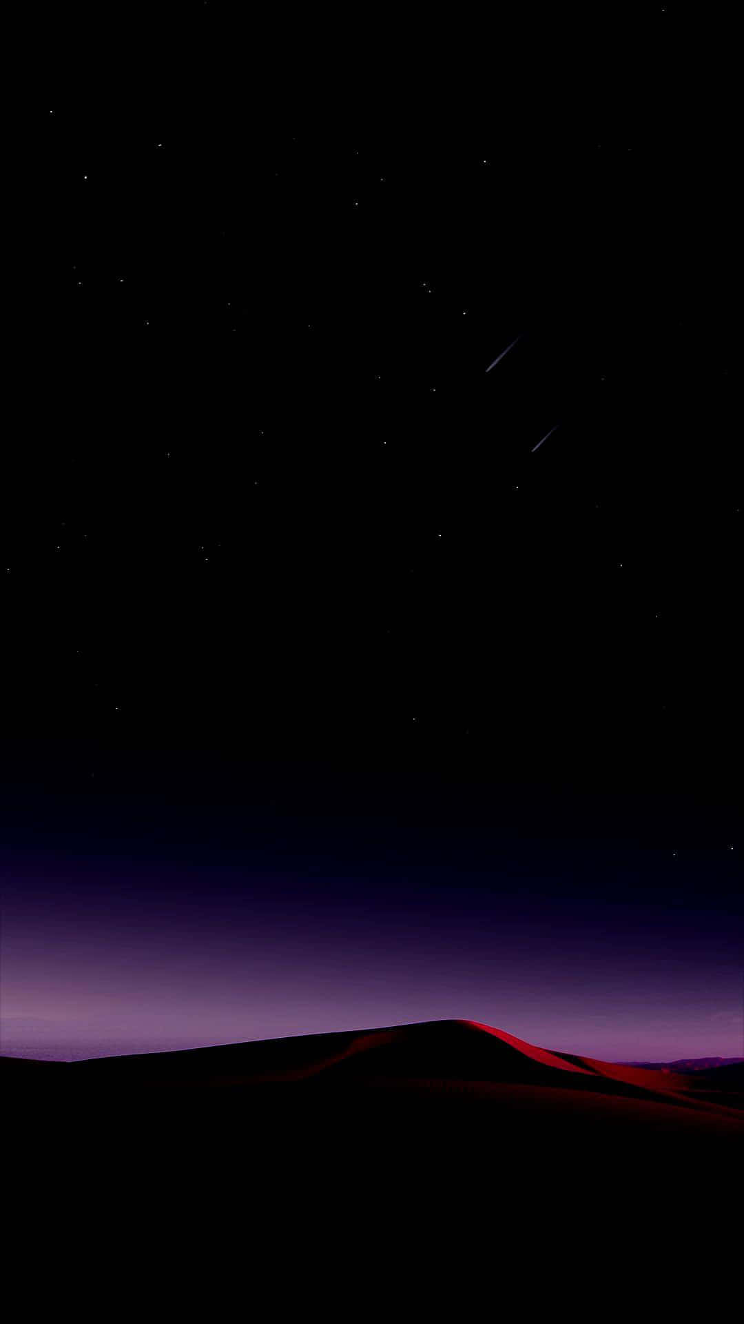 在繁星點點的夜空下，黑暗的沙漠沙丘與流星。