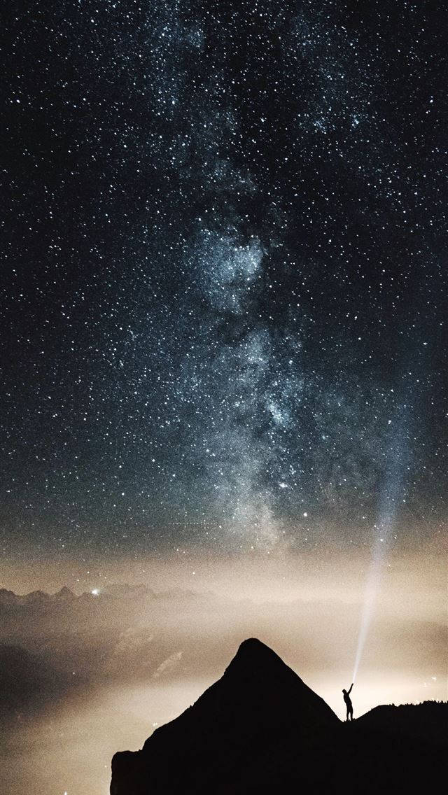 山頂上的人將手電筒照向星空