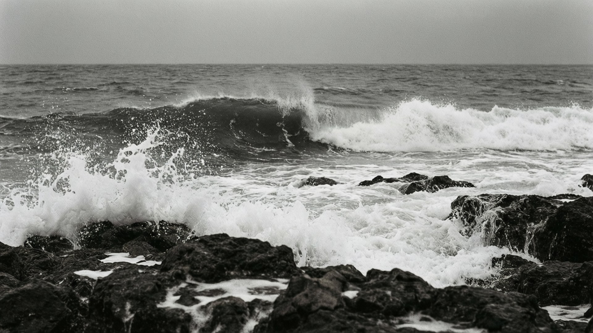 海浪拍打黑暗岩石海岸的黑白畫面