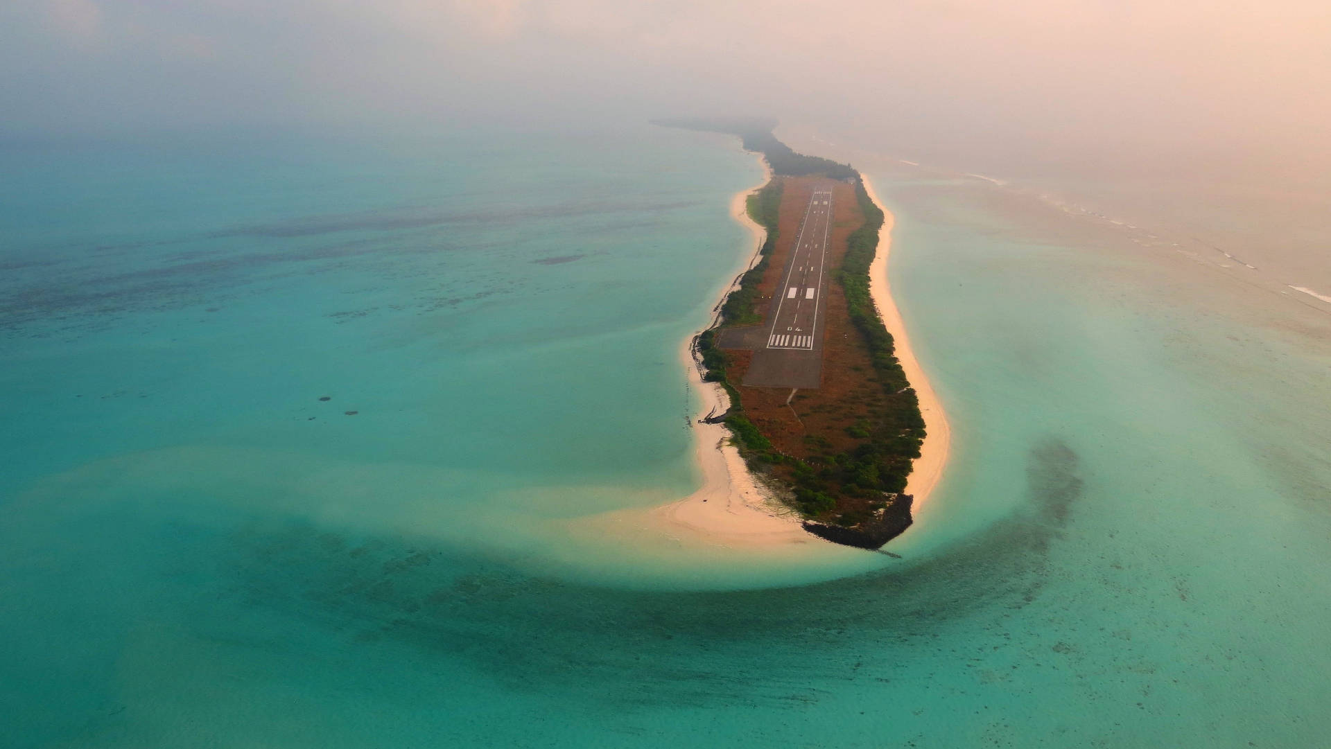 日出時分，在熱帶島嶼上建造的跑道，周圍環繞著碧綠海水。