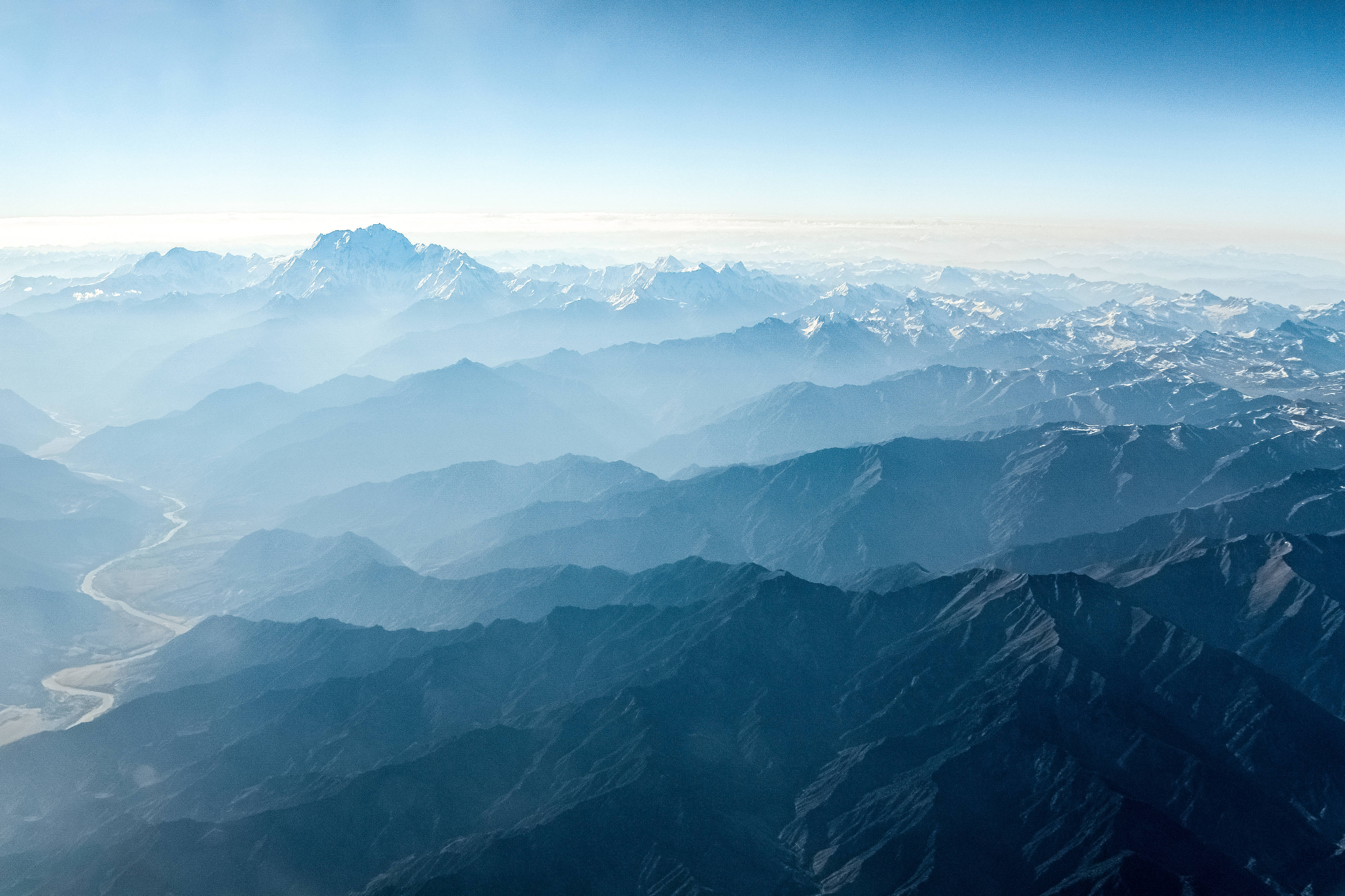 崎嶇山地地形 壁紙 — 從高空俯瞰層層疊疊的山脈，在清澈藍天下逐漸融入大氣薄霧中。