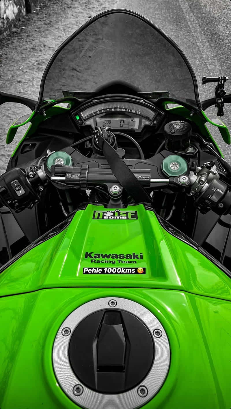綠色Kawasaki賽車電單車儀表板，帶有1000kms貼紙，位於碎石路上。