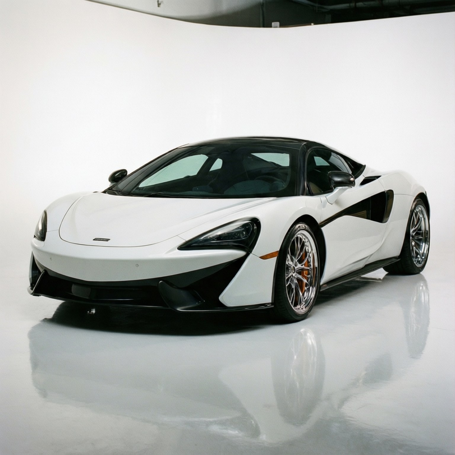 白色McLaren跑車，帶有黑色飾件和金色制動卡鉗，在一個帶有反射地板的工作室中。