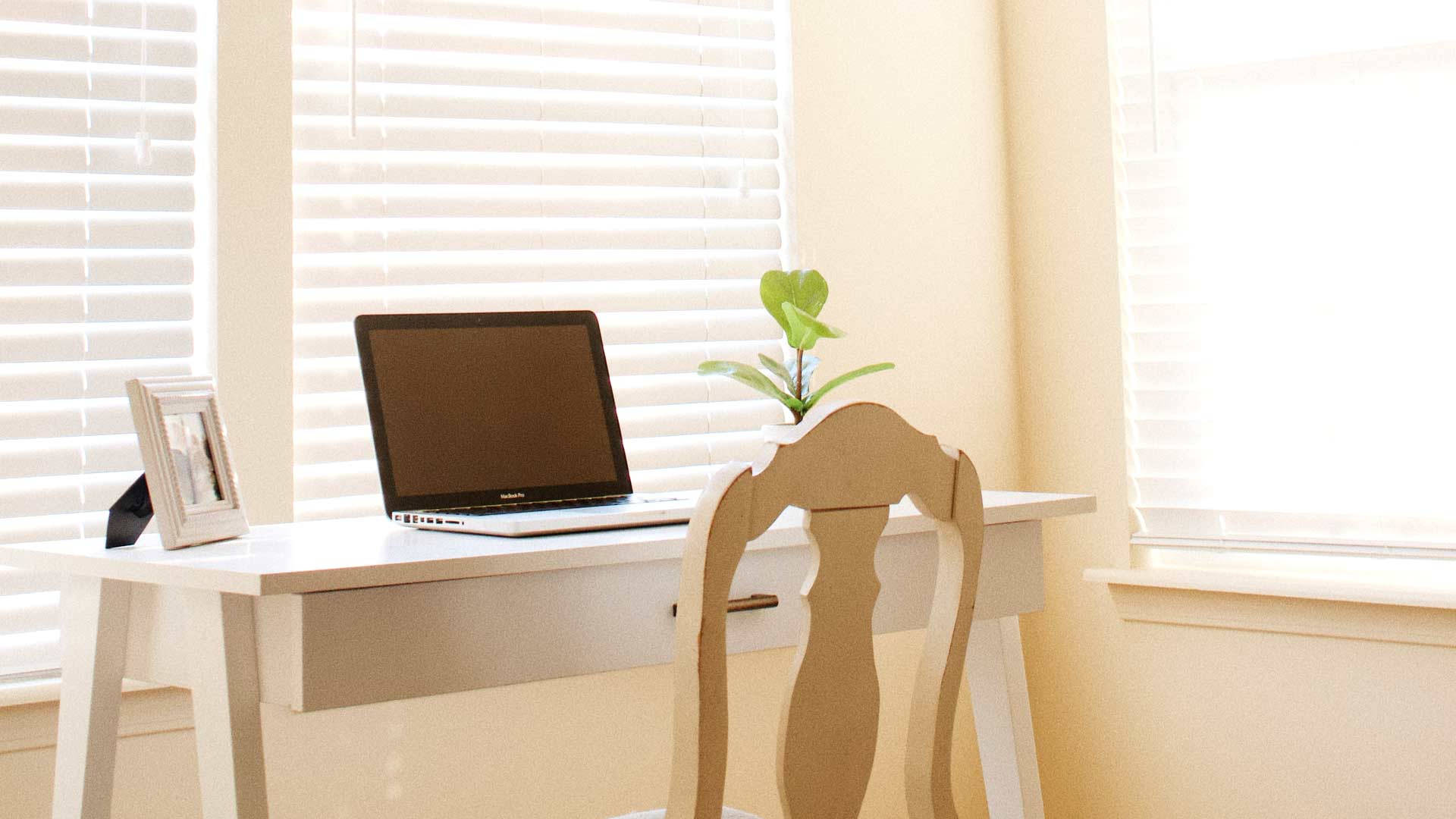 白色書桌，手提電腦和植物，靠近窗簾的窗戶