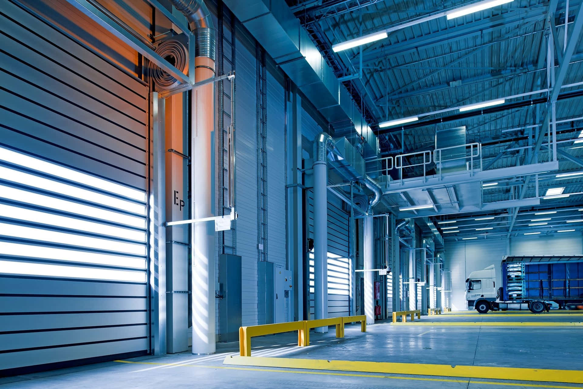 大型倉庫內部，半掛卡車在裝卸碼頭，明亮的螢光燈下。
