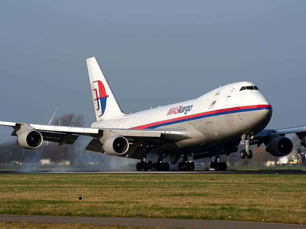 MASkargo波音747貨機降落在跑道上，揚起灰塵雲。