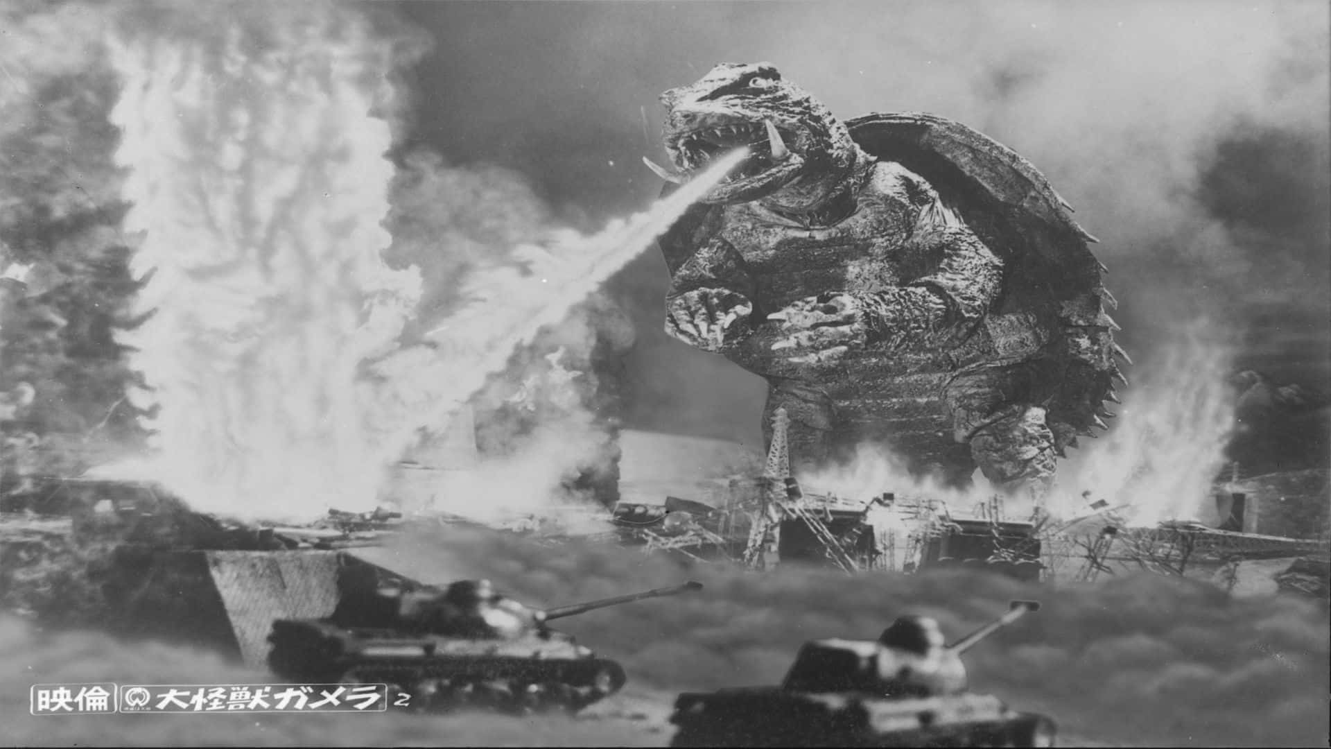 Gamera 桌布 壁紙 — 巨大的哥斯拉在燃燒的坦克和煙霧的戰場上釋放原子吐息。