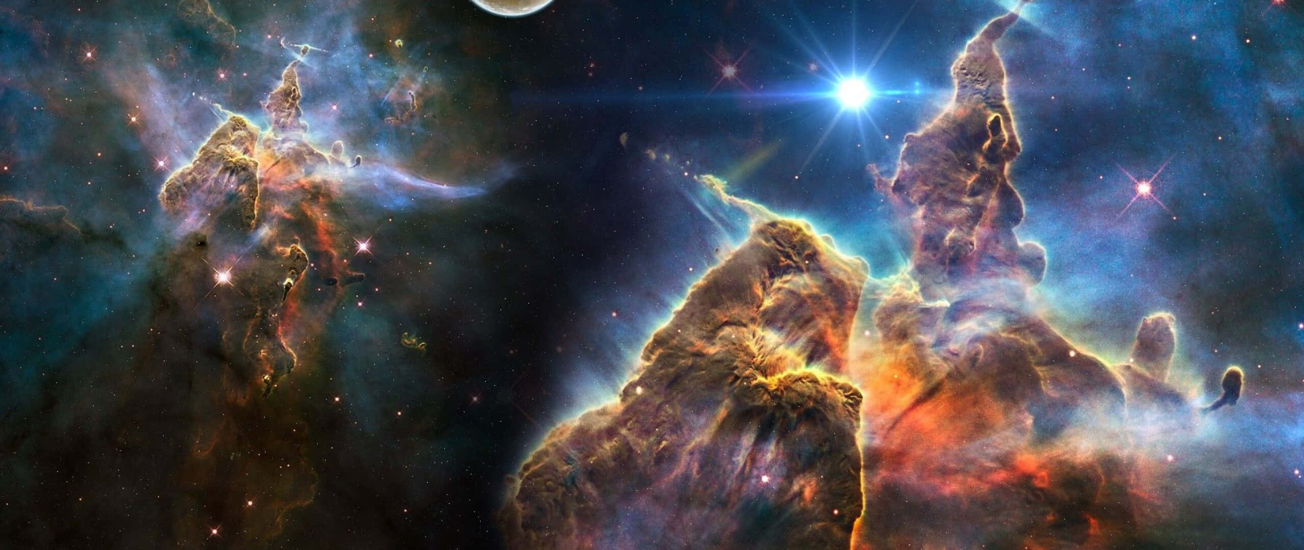 Carina Nebula 桌布 壁紙 — 巨大的氣體和塵埃宇宙柱在佈滿星辰的虛空中散發出火橙色和電光藍色的光芒。