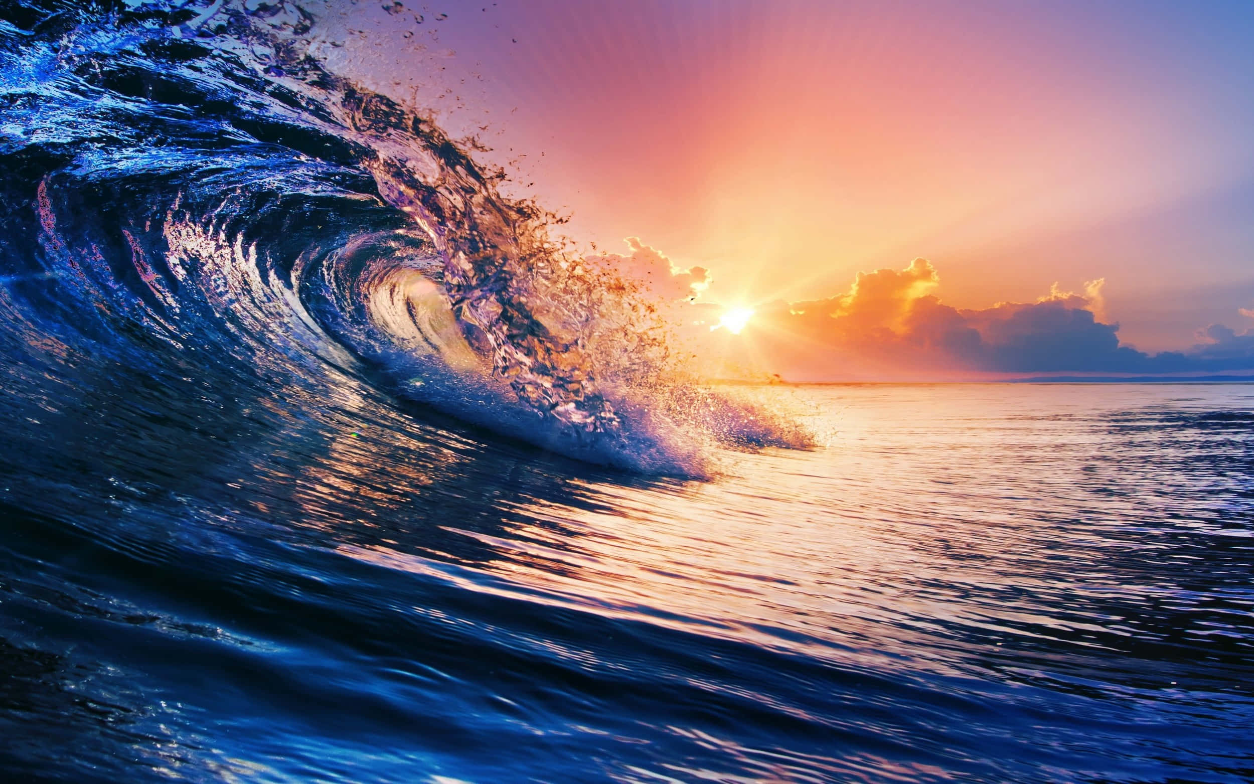 Sunset Ocean 桌布 壁紙 — 巨大的海浪在日落時戲劇性地捲起，伴隨著熾熱的橙色陽光和深藍色的海水。