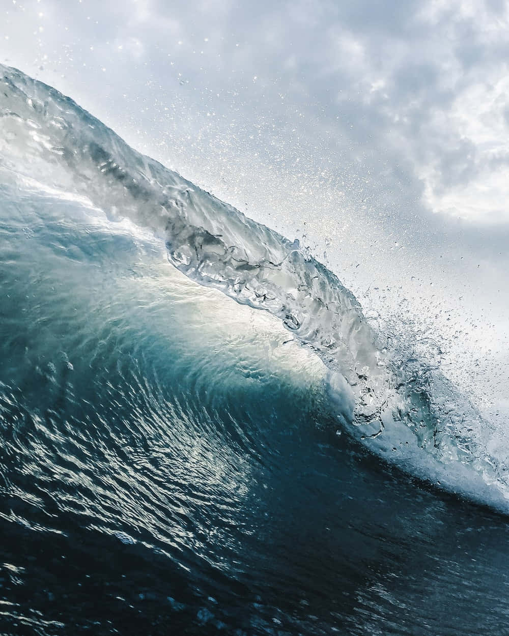waves 桌布 壁紙 — 巨大的海浪在頭頂翻捲，帶著白色泡沫飛濺，映襯著多雲的天空。