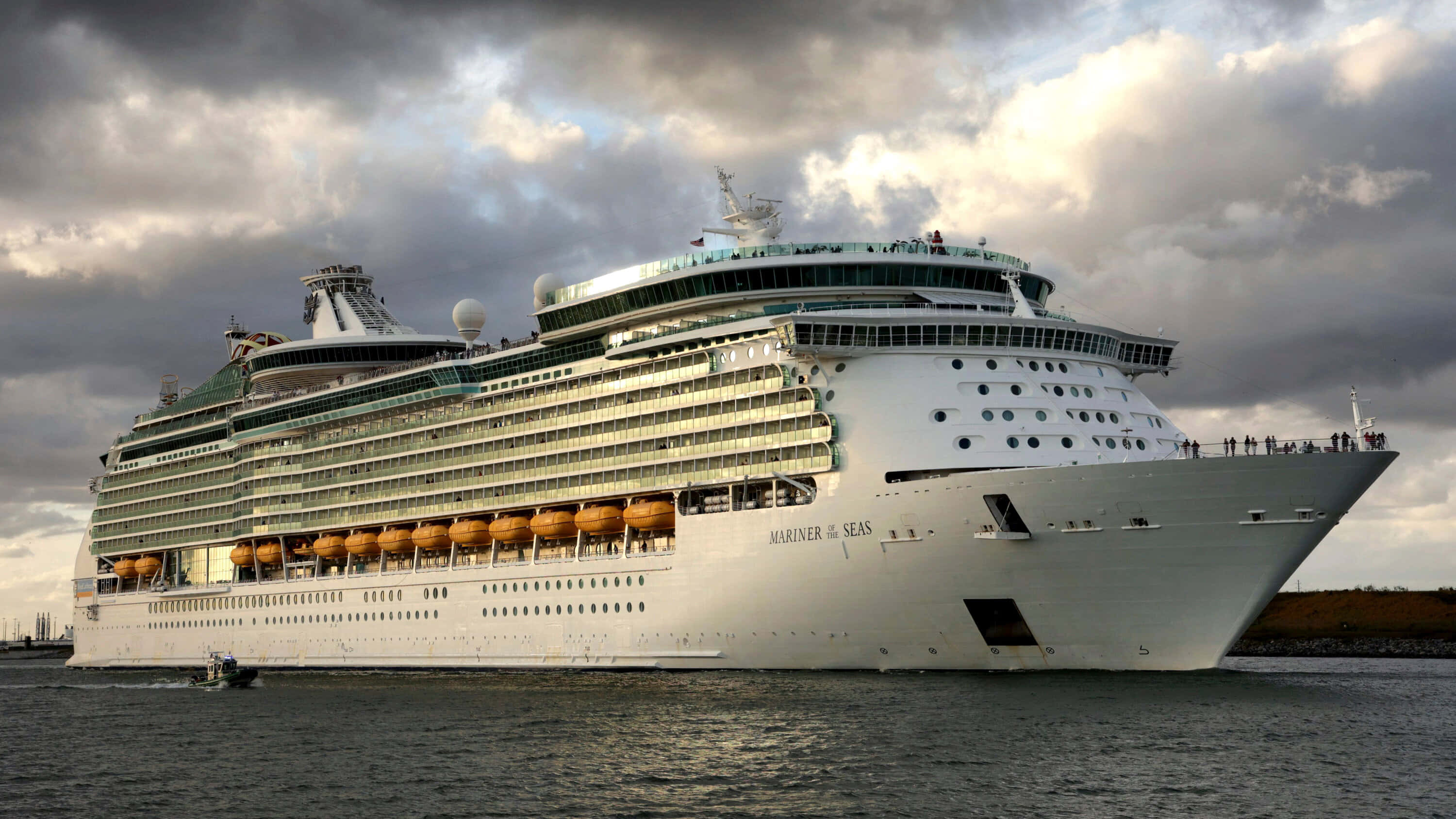 Cruise Ship 桌布 壁紙 — 巨大的白色郵輪海洋水手號在戲劇性的多雲天空下航行，甲板上可見乘客。