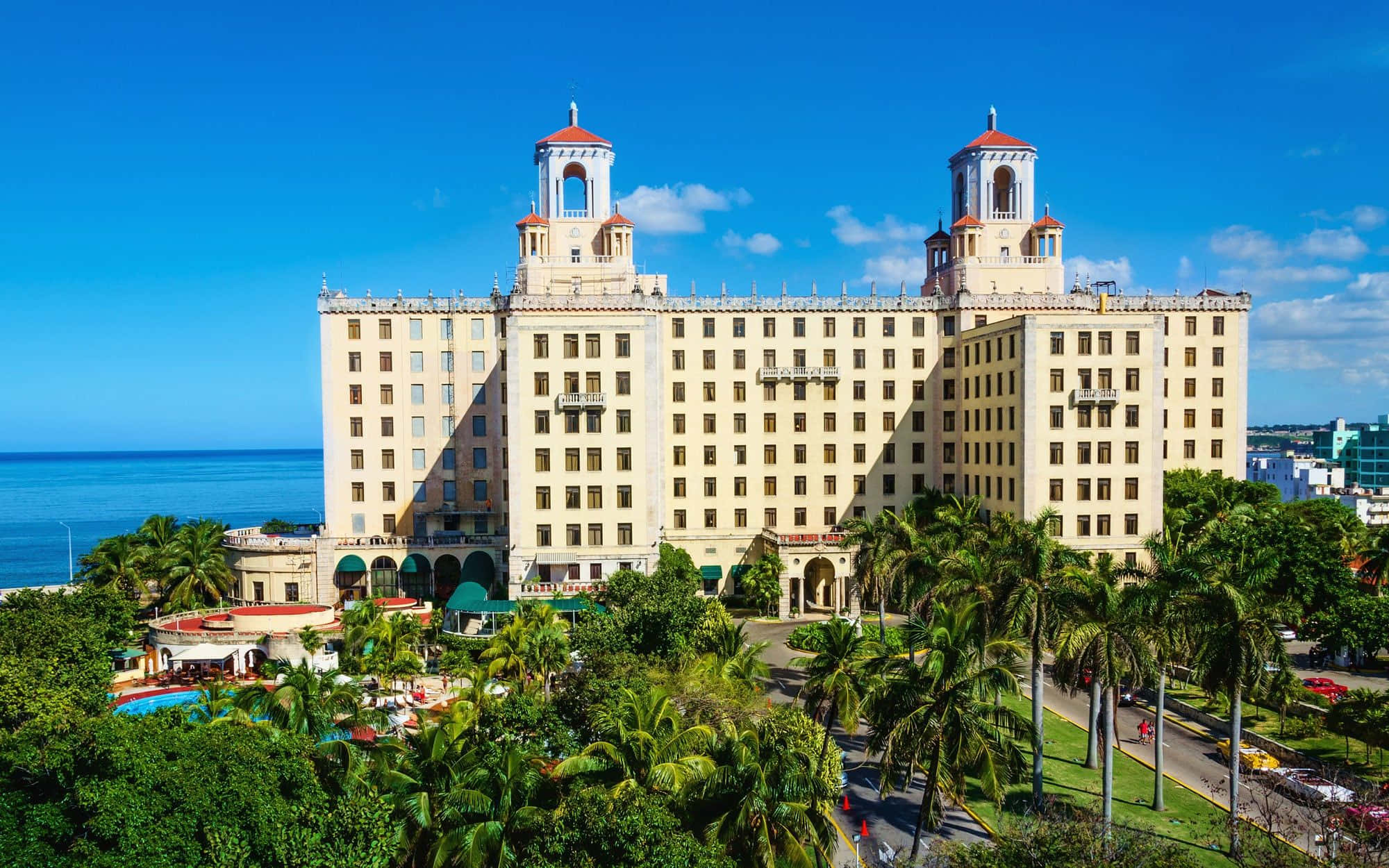 Cuba 桌布 壁紙 — 巨大的米色雙塔酒店雄偉地矗立在海洋邊，天空湛藍，點綴著蓬鬆的白雲。