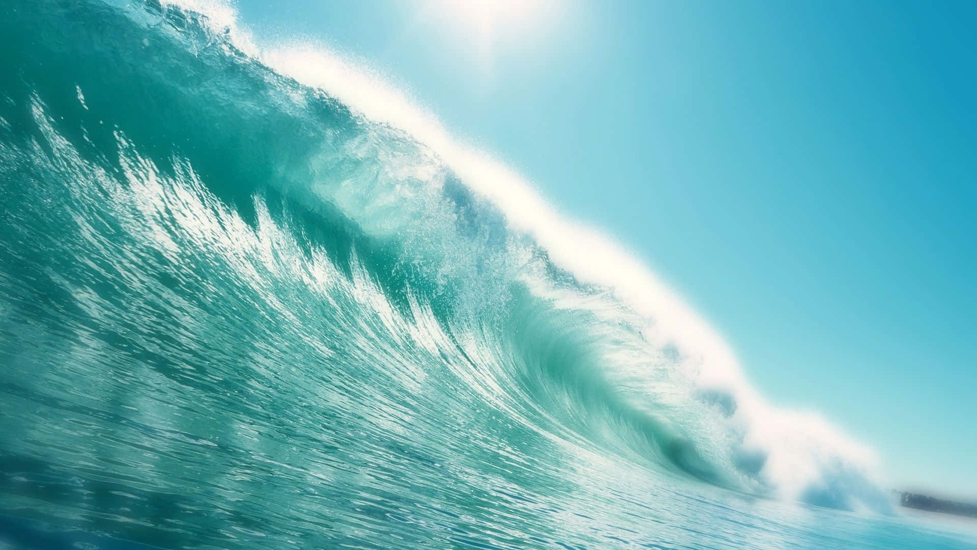 Tides 桌布 壁紙 — 巨大的藍綠色海浪在明亮的陽光下翻滾，帶著閃閃發光的白色泡沫，映襯著清澈的藍天。