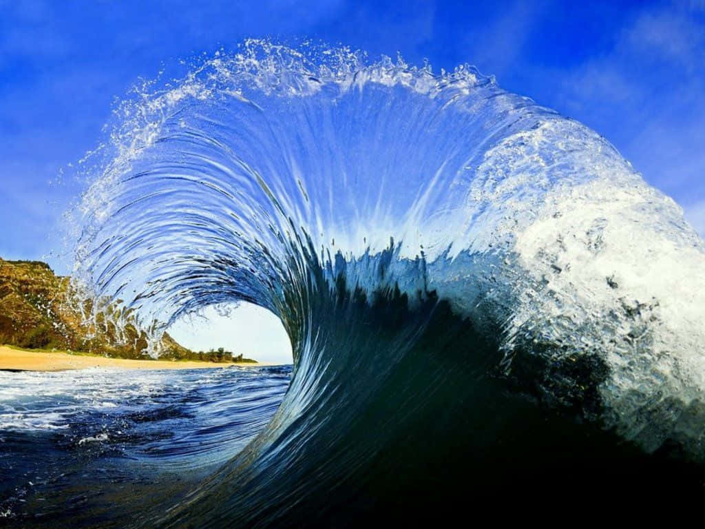 海浪 桌布 壁紙 — 巨大的藍綠色海浪捲成一個完美的桶狀，帶著水花，映襯著清澈的藍天和沙灘。