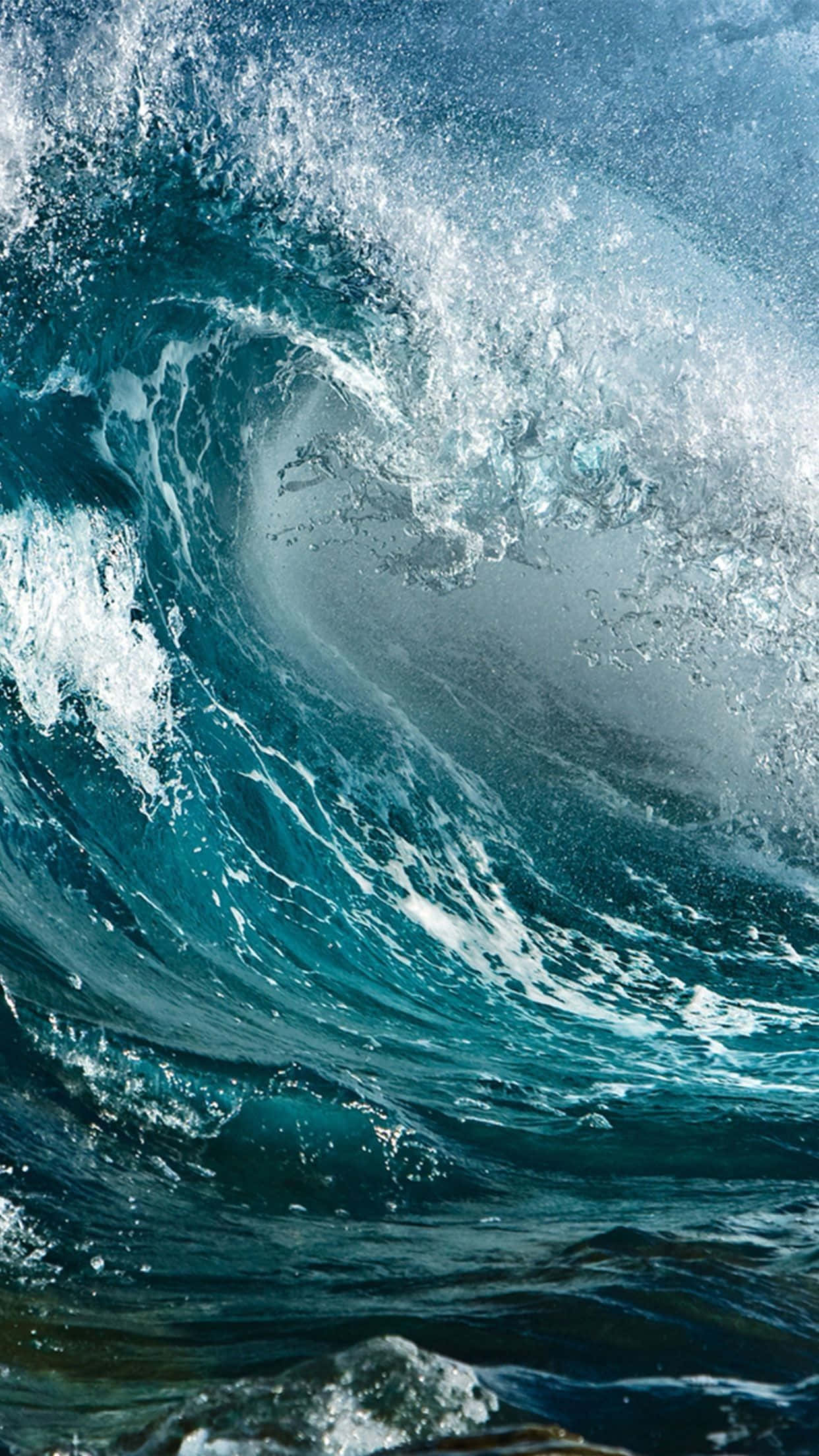 waves 桌布 壁紙 — 巨大的藍綠色海浪捲成完美的筒狀，伴隨著泡沫般的白色浪花，映襯著明亮的藍天。