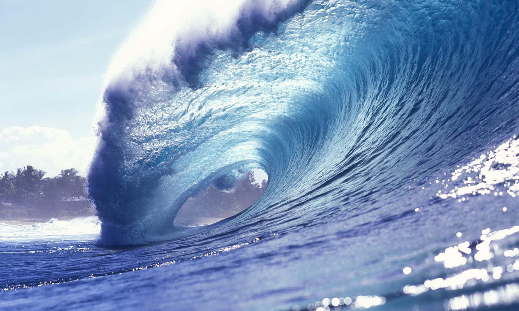 waves 桌布 壁紙 — 巨大的藍綠色海浪捲成完美的筒狀，水花四濺，陽光在水面上閃爍。