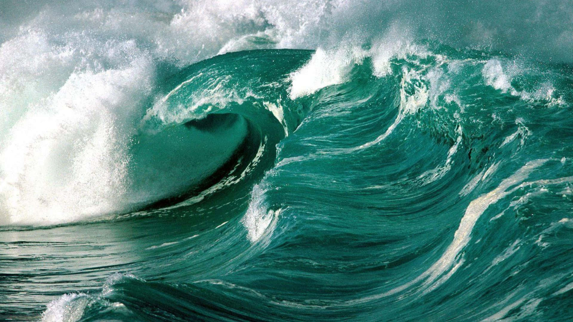 Beautiful Ocean 桌布 壁紙 — 巨大的藍綠色海浪捲成完美的筒狀，伴隨著泡沫般的白色飛沫，映襯著暴風雨的天空。
