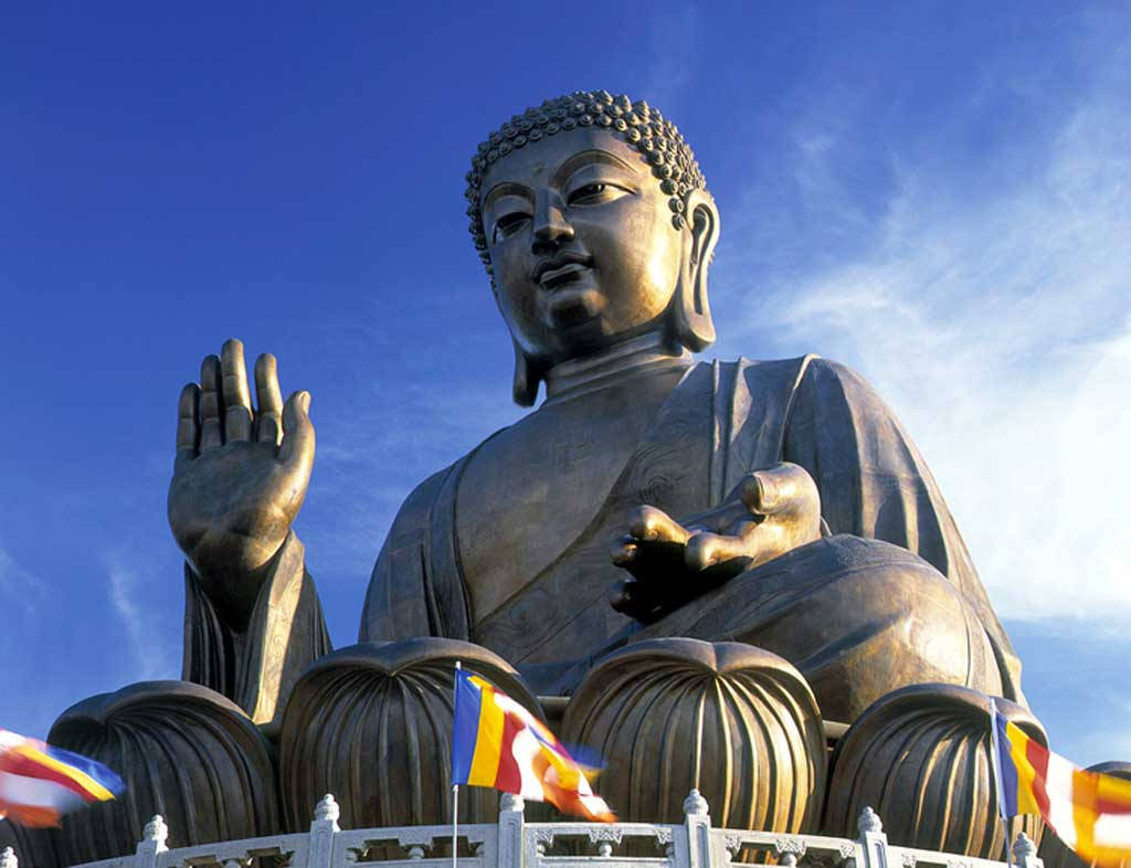 藍天下帶有經幡的大型金色佛像。