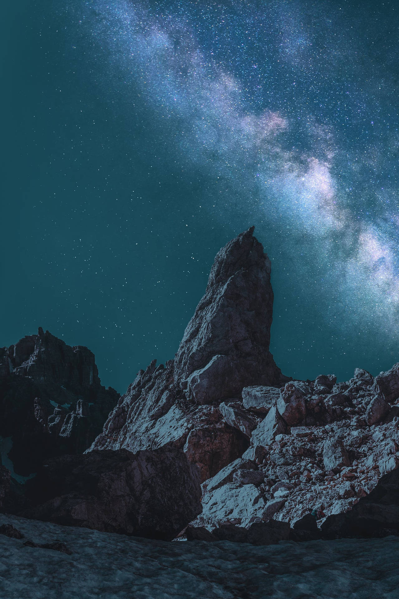 在繁星點點的夜空下，一座岩石山脈，銀河系清晰可見。