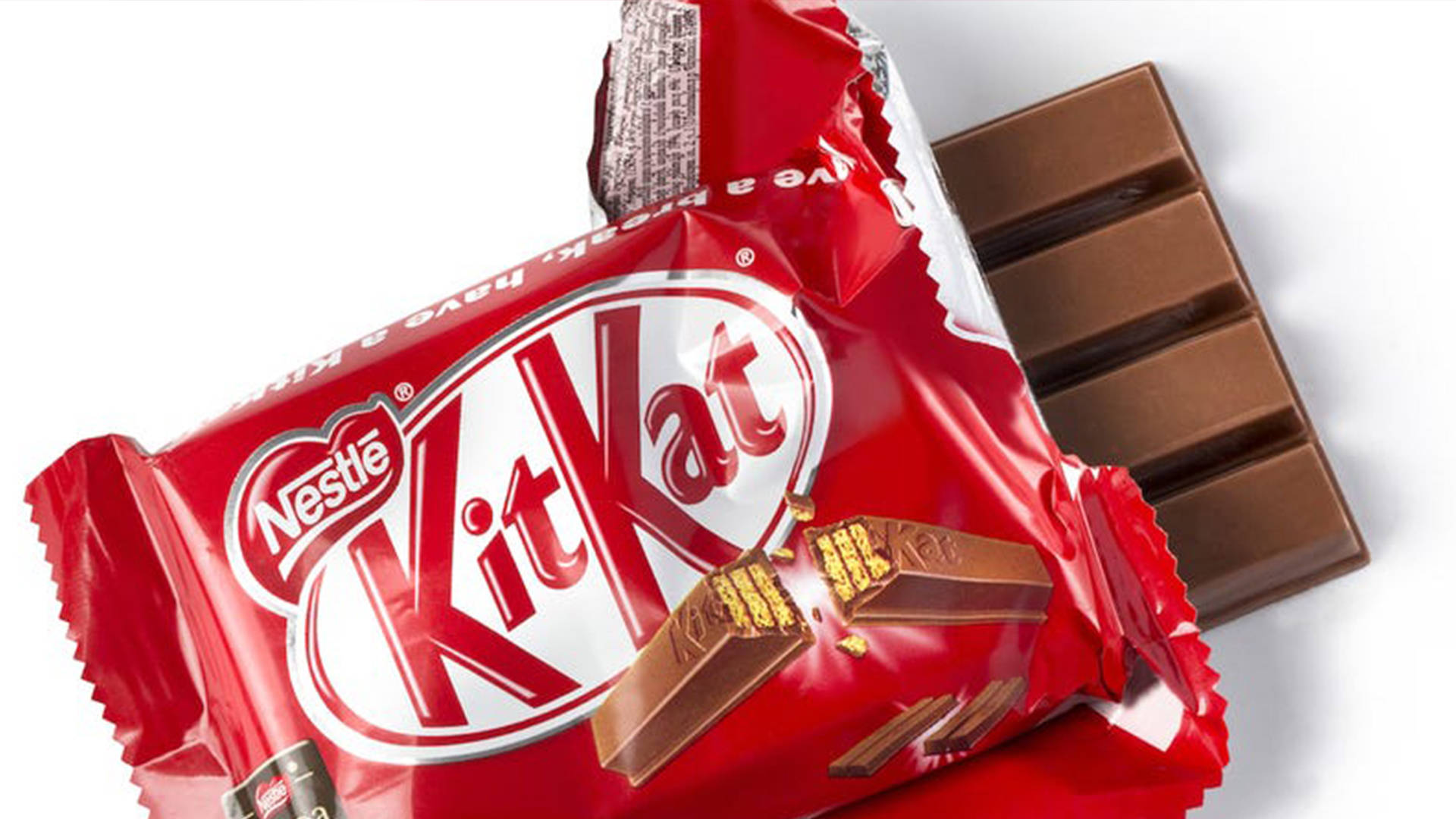 已開封的Kit Kat巧克力 壁紙 — 部分拆開的 KitKat 朱古力棒，紅色錫紙包裝，破開的部份露出牛奶朱古力和威化。