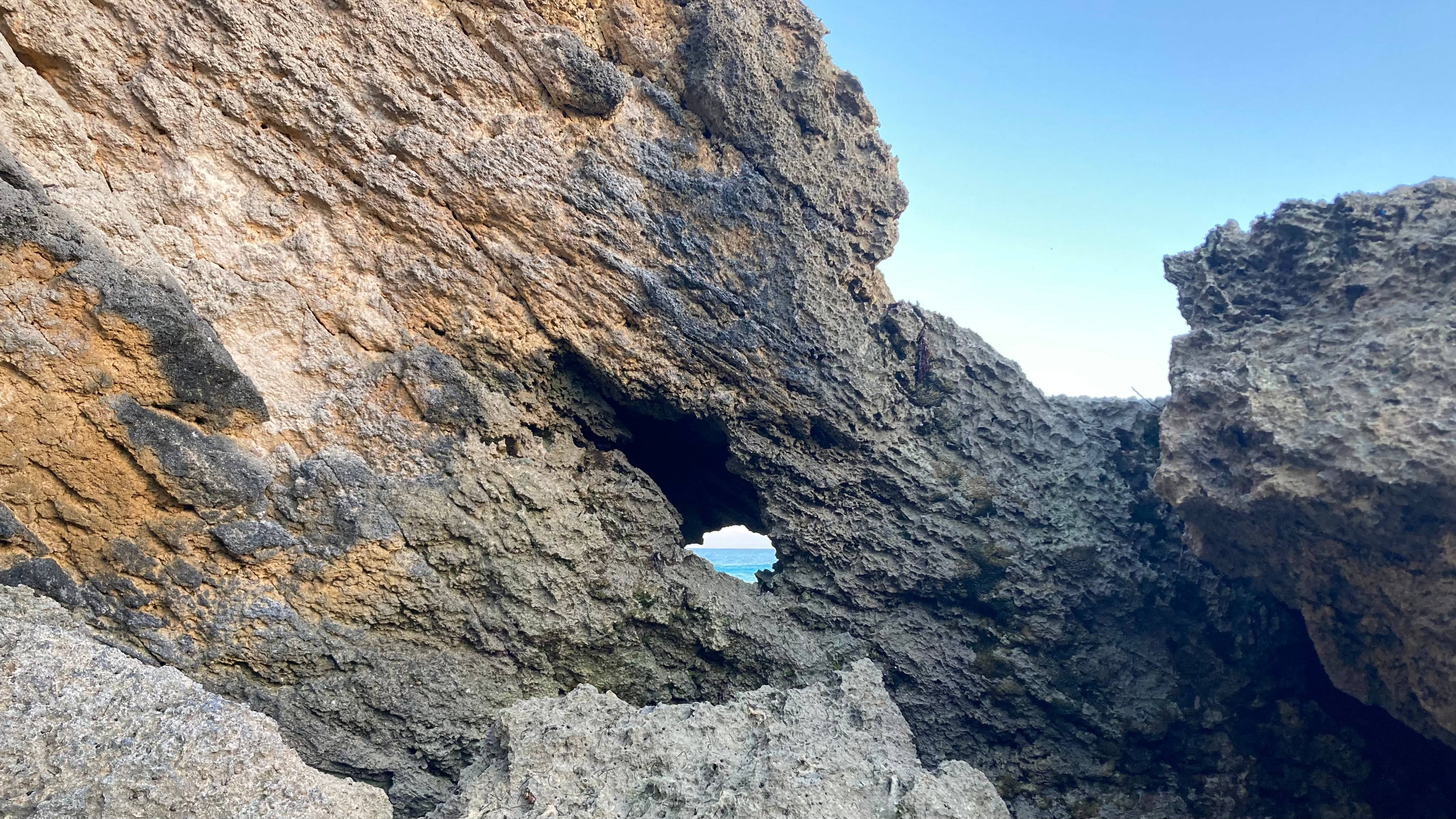 巴哈馬堅硬石灰岩 壁紙 — 天然岩石拱門框住藍天白雲下嘅碧綠海洋。