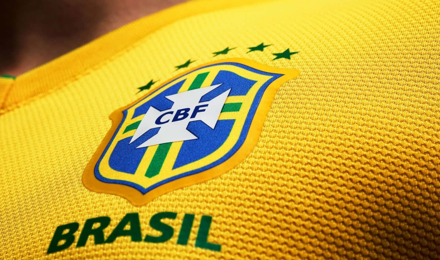 Brazil 桌布 壁紙 — 巴西CBF徽章近距離特寫，位於有紋理的黃色足球球衣上，帶有綠色星星和'BRASIL'文字。
