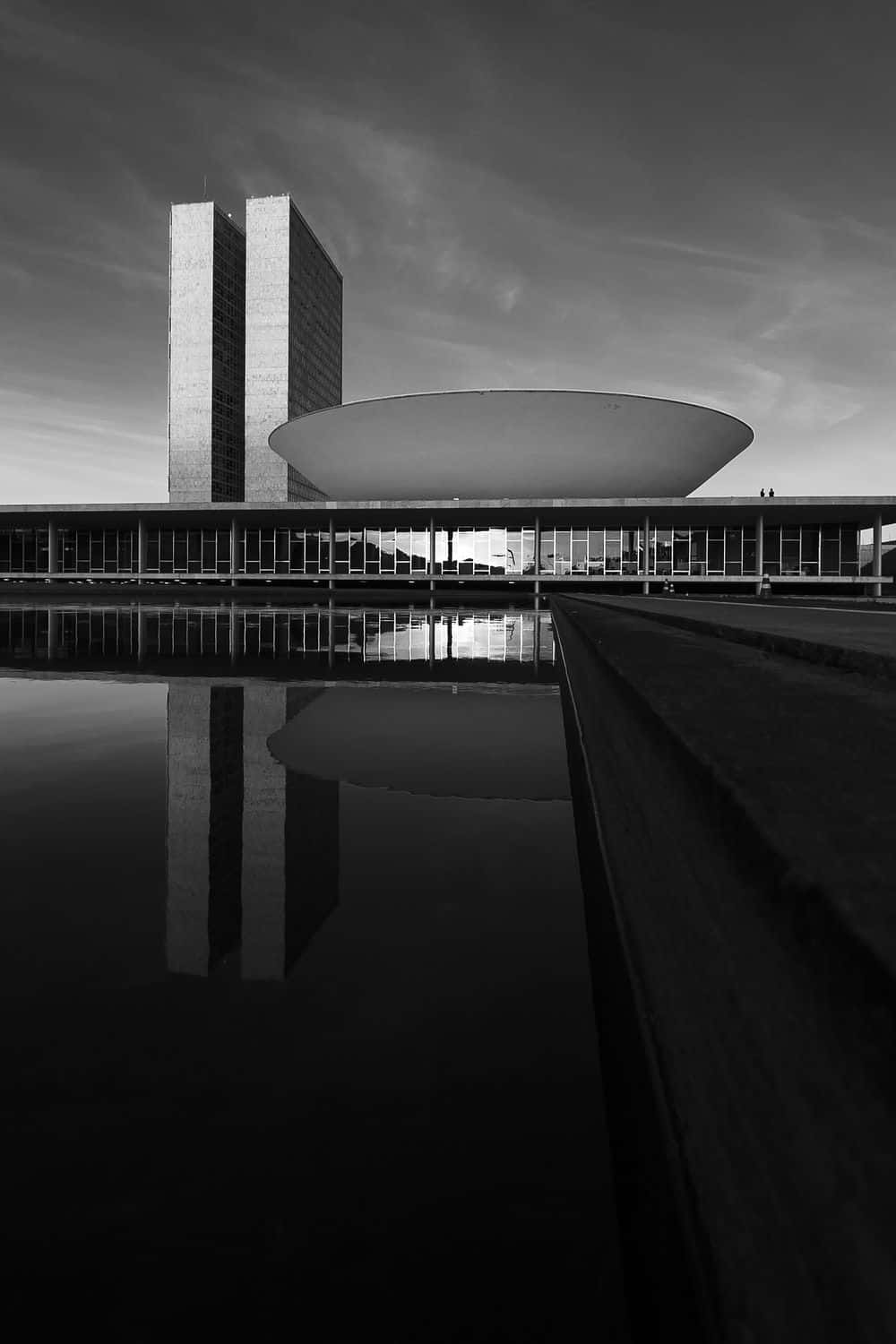 Black And White Architecture 桌布 壁紙 — 巴西國會大廈的單色建築照片，其標誌性塔樓和圓頂倒映在平靜的水面上。