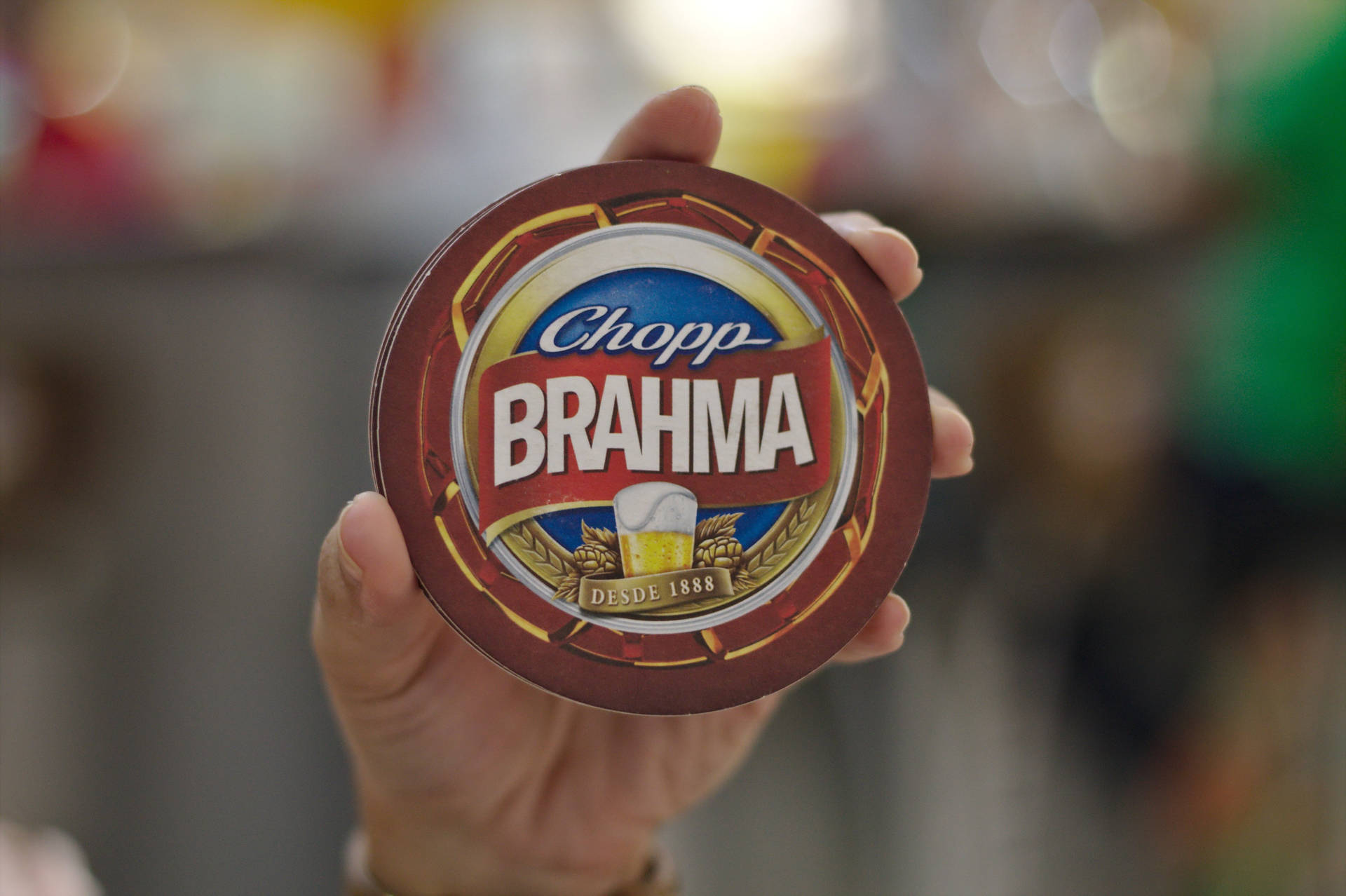手拿著帶有標誌和小麥設計的 Brahma 啤酒杯墊。